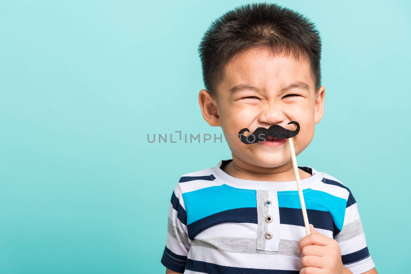 Funny happy hipster kid holding black mustache props for the photo booth close face, studio shot isolated on a blue background, Men health awareness, Prostate Cancer Awareness