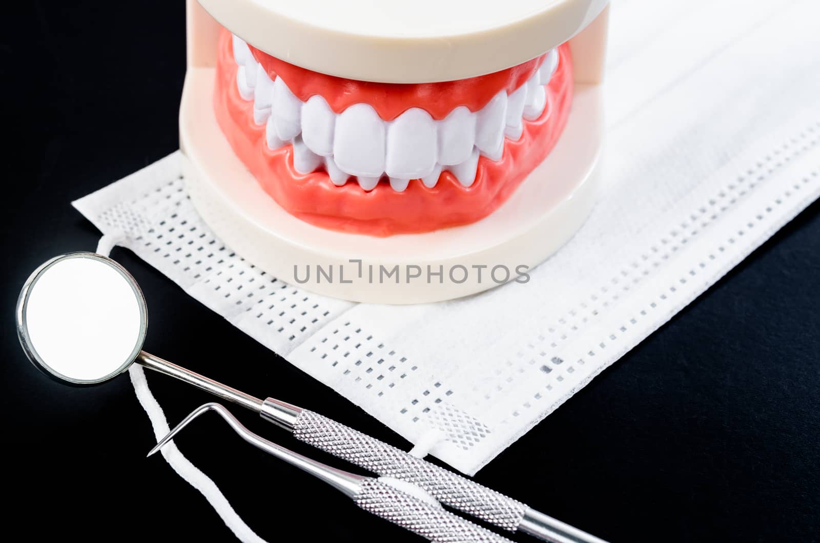 Set of metal Dentist's medical equipment tools with model teeth. by Gamjai