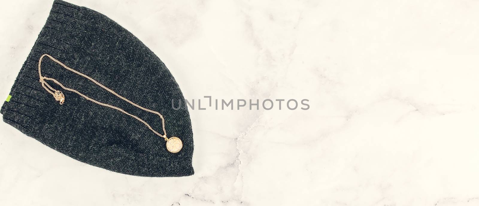 Gold nuggets in a round glass rose gold pendant and chain on a black wool beanie with text copy space