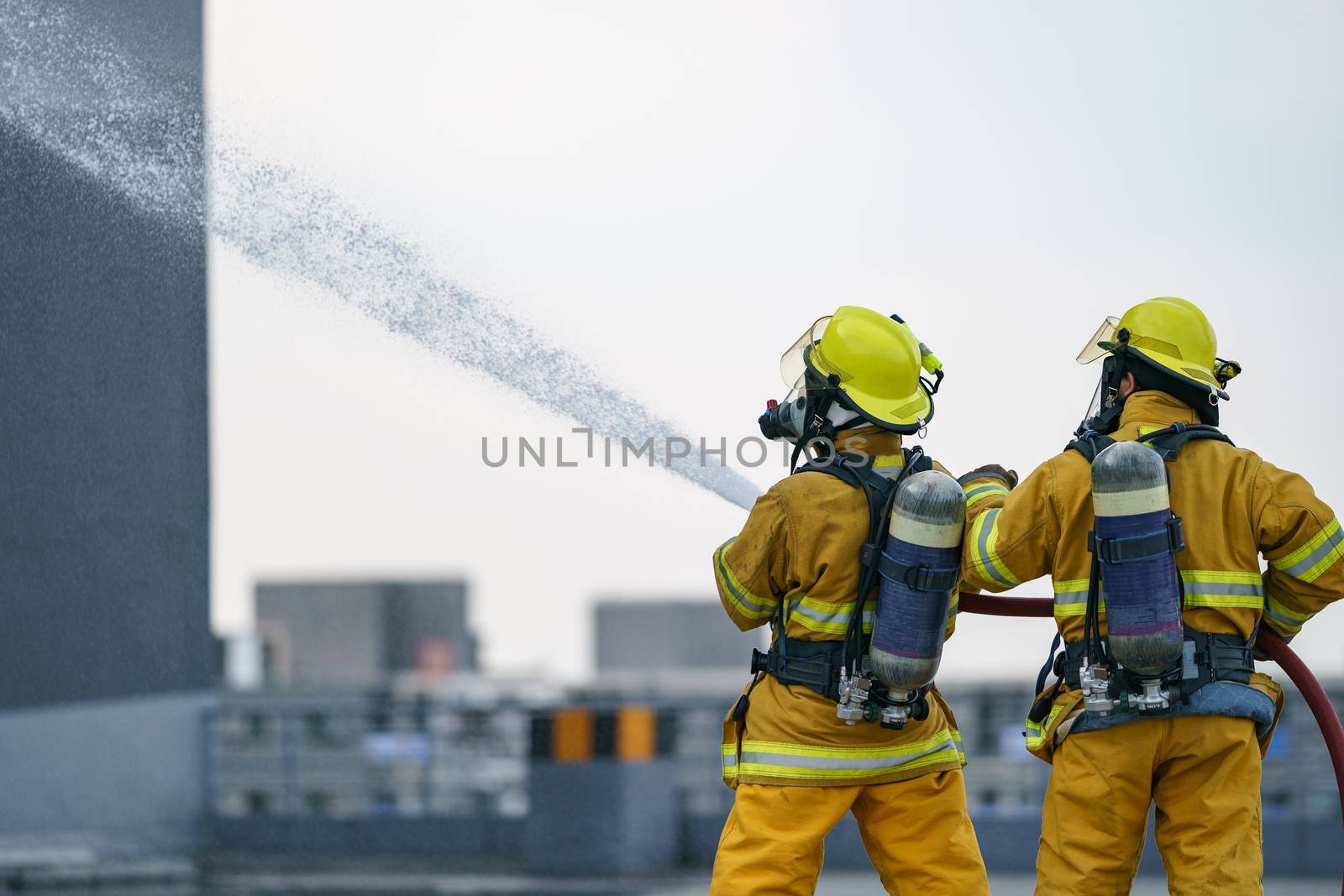 Firefighter or fireman team work water spray by high pressure nozzle to fire.