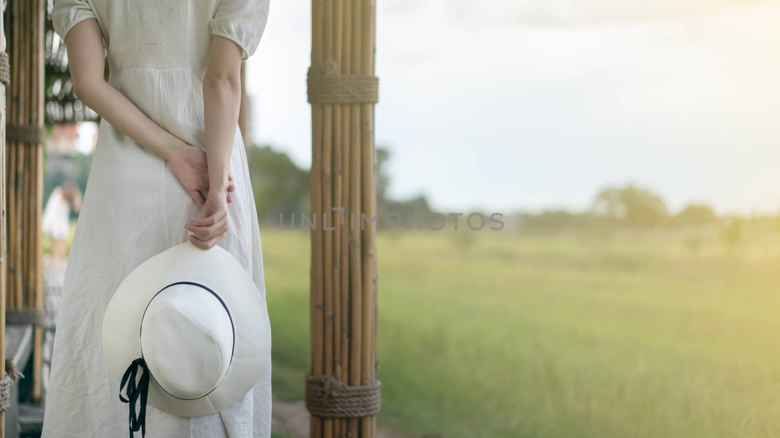 Woman in white dress walking on Bamboo tunnel and bridge as the walk way through the rice field.