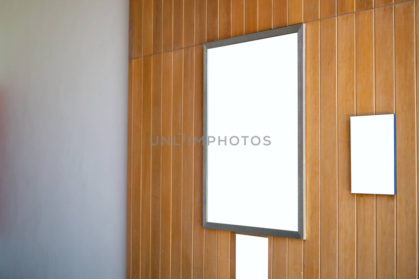 Mock up blank poster frame hanging on wooden wall in room.