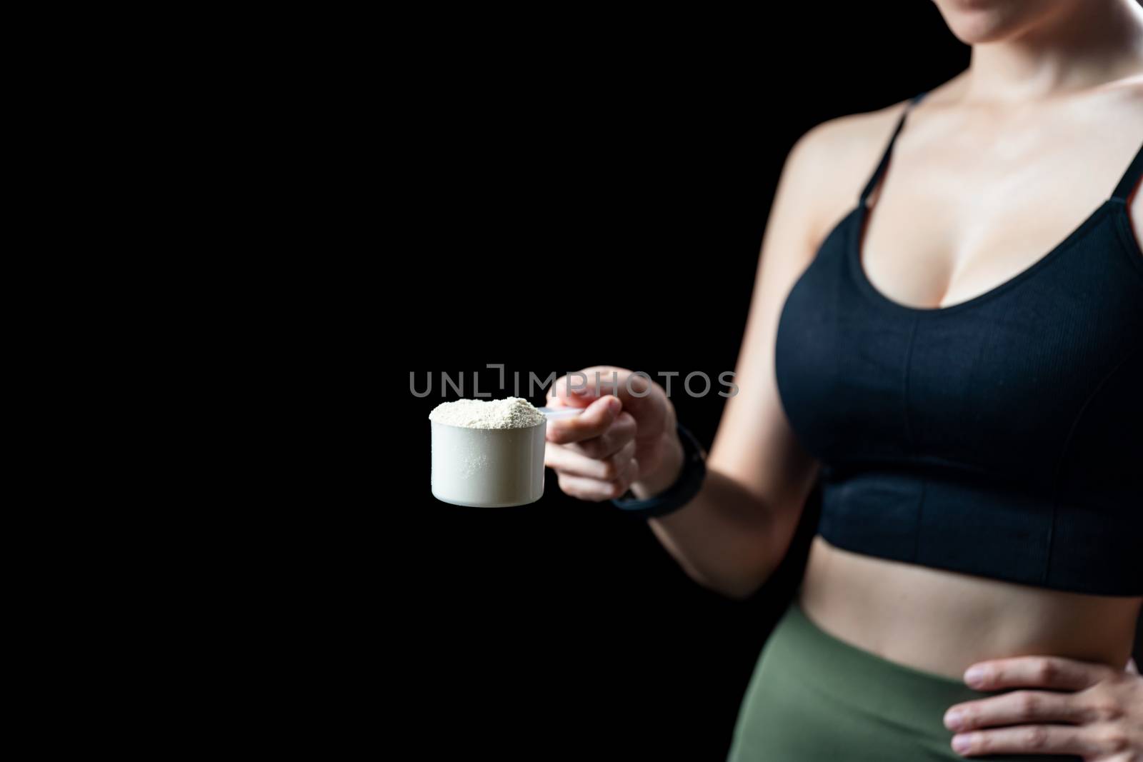 Close up of women hand holding measuring scoop of whey protein preparing protein shake.