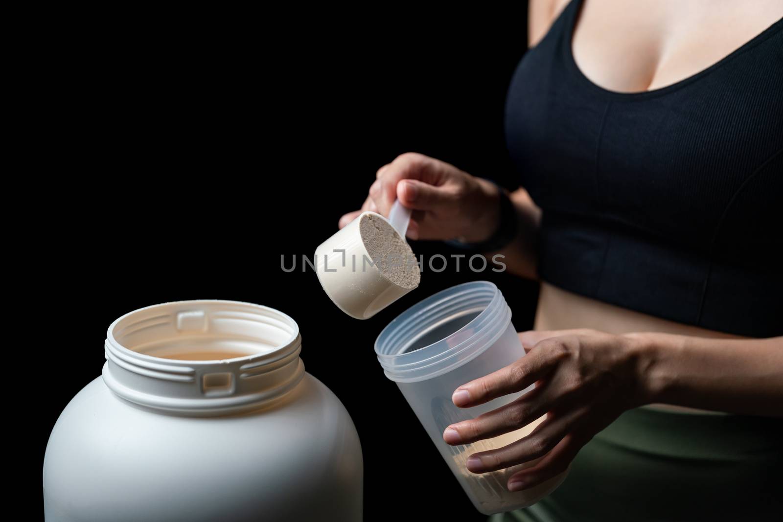 Close up of women with measuring scoop of whey protein, jar and by sirawit99