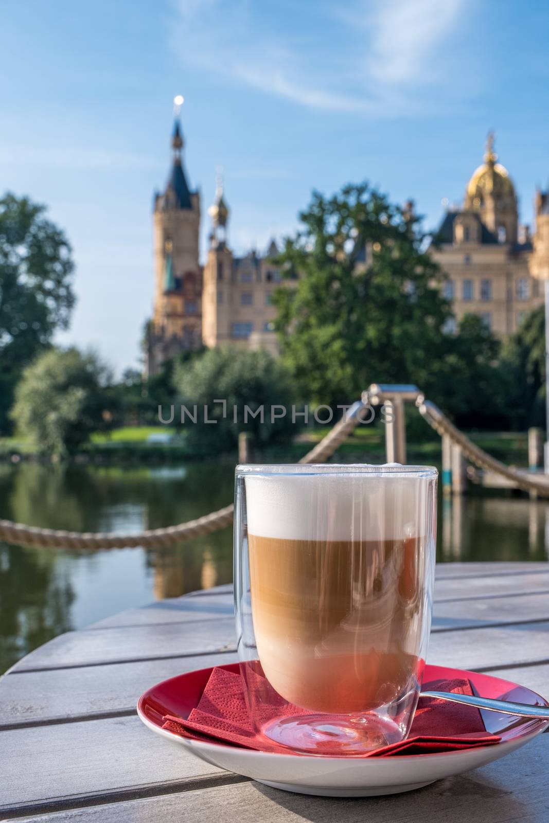 Cup of cappuccino in an outdoor cafe or restaurant on a summer day with a beautiful castle in Schwerin in the background.