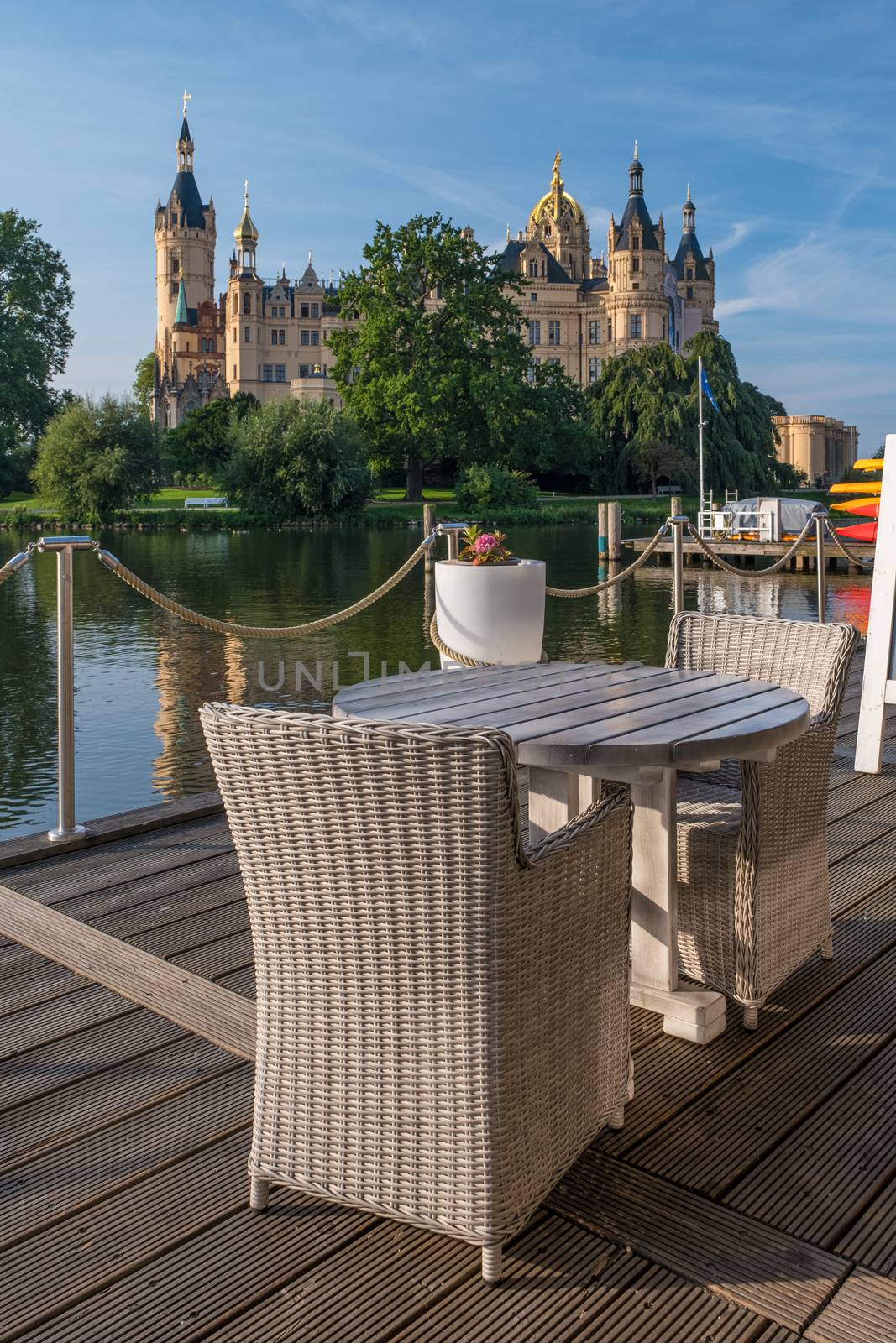 Empty chairs in cafe with a beautiful castle in Schwerin in the background. by Fischeron