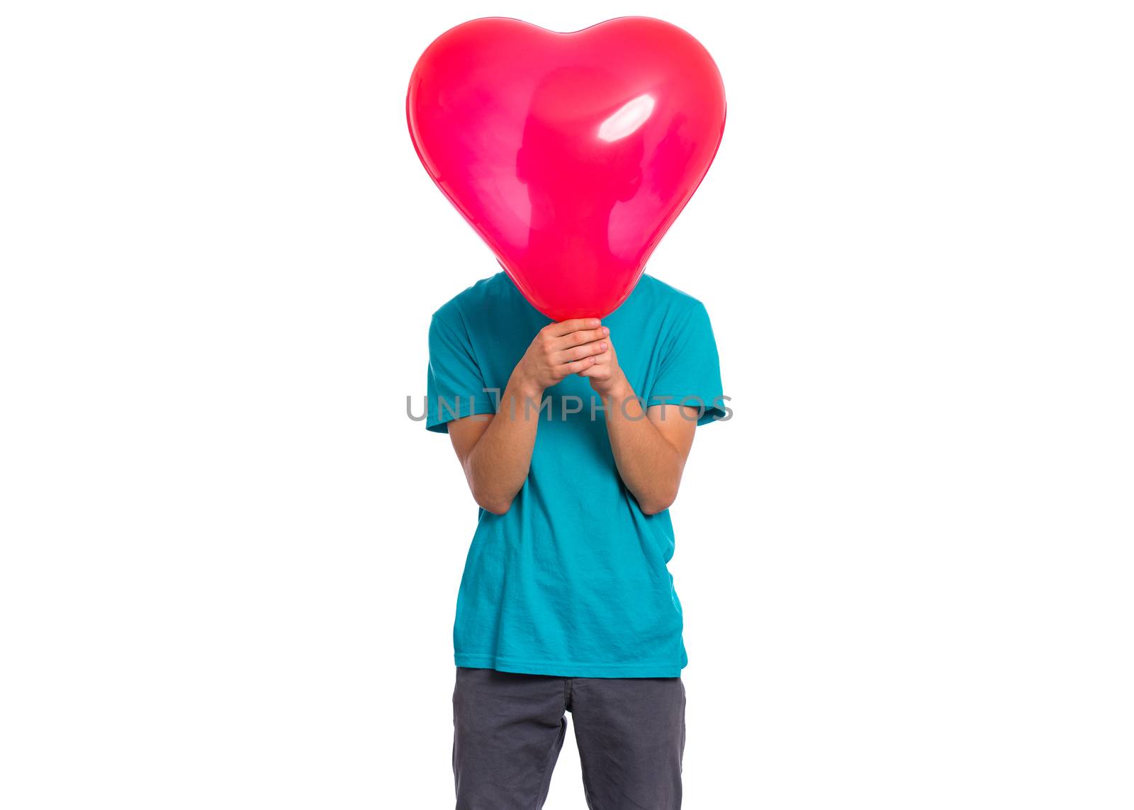 Teen boy hiding behind red heart shaped balloon. Child holding symbol of love, family, hope. Celebration of Saint Valentines Day. Teenager cover face isolated on white background.