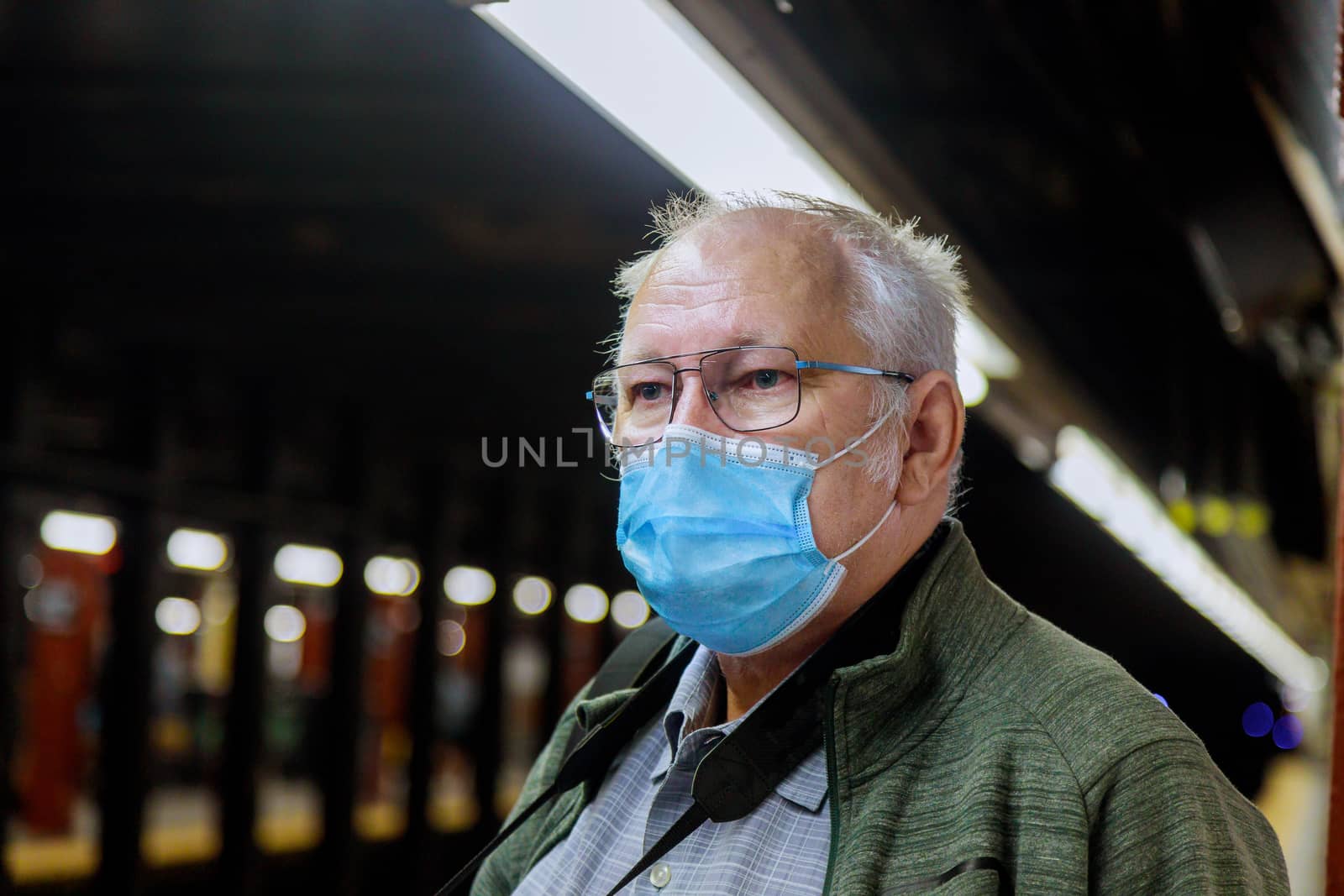 Safety in a public place while epidemic mature man wearing disposable medical face mask of the subway in New York during coronavirus outbreak covid-19 by ungvar