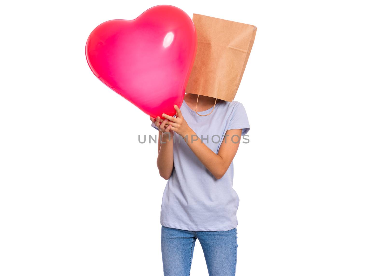 Valentines Day concept. Teen girl with paper bag over head holds red heart shaped balloon, isolated on white background. Child holding symbol of love, family, hope. Teenager cover head with bag.