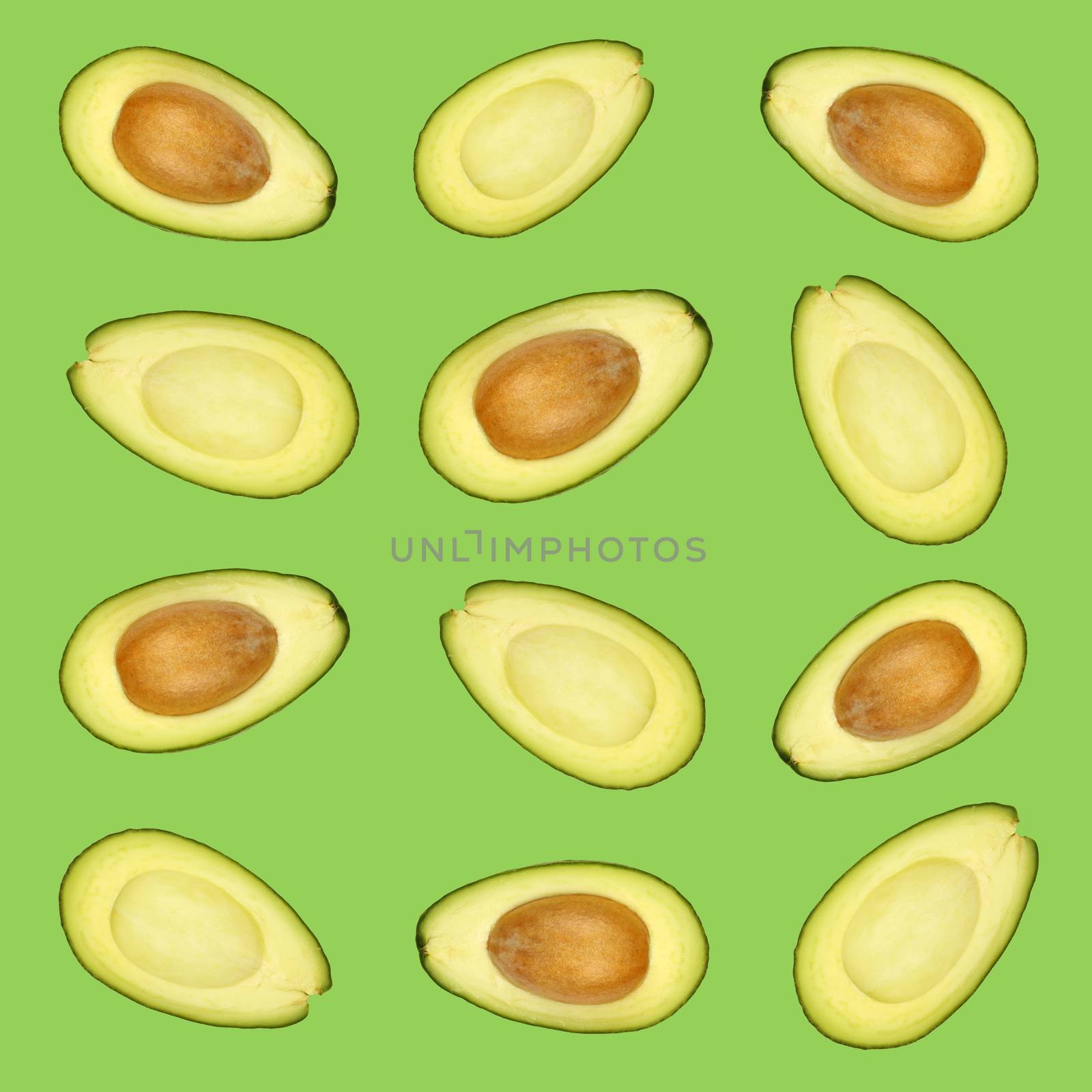 Pattern of fresh halved cut avocados over green background