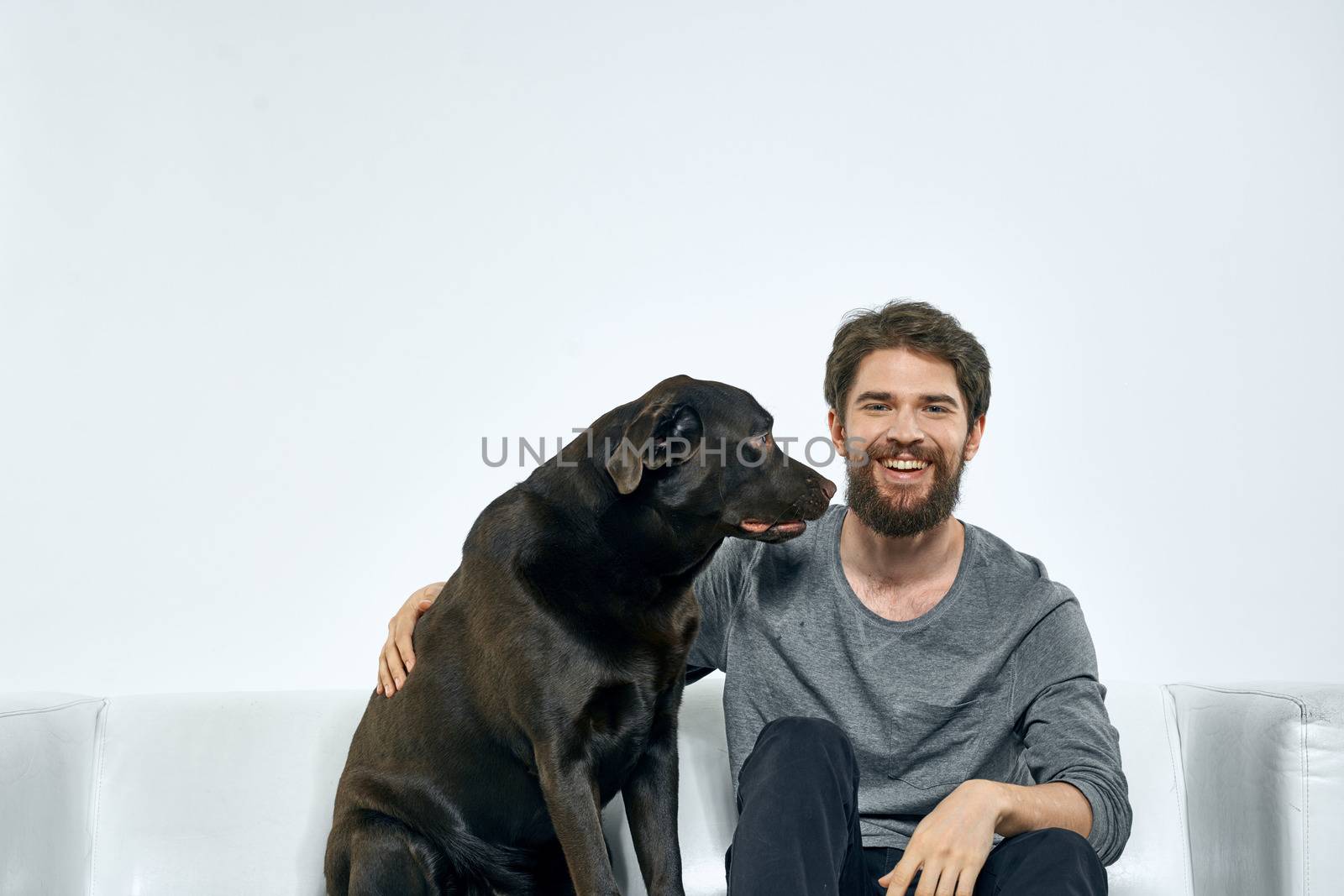 Man with a pet dog on the couch fun friends emotions light room. High quality photo