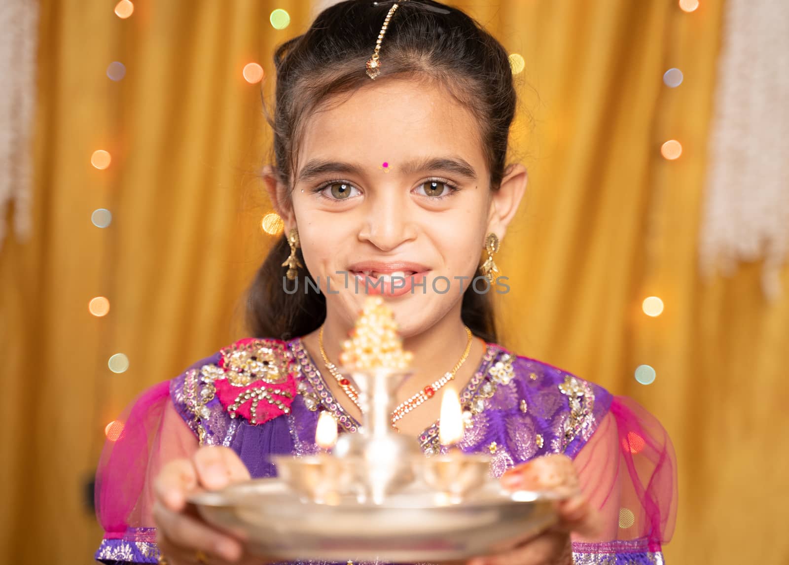 POV shot of cute little girl in traditional dress doing aarti or offering light to god during Hindu Religious festival ceremony. by lakshmiprasad.maski@gmai.com