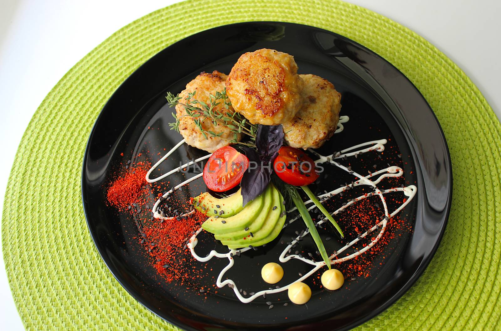On a black plate zucchini with fried cutlets are beautifully decorated with mayonnaise and herbs with seasoning