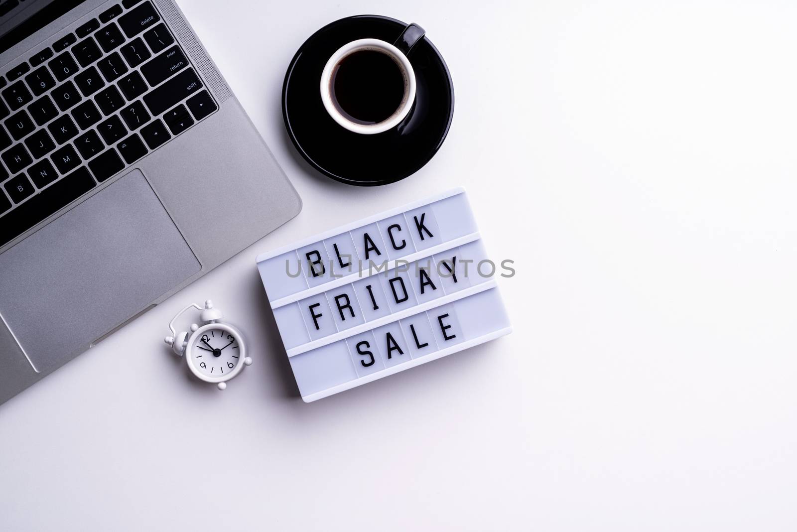 Black Friday Sale words on lightbox with cup of coffee, laptop and clock top view flat lay on white background by Desperada