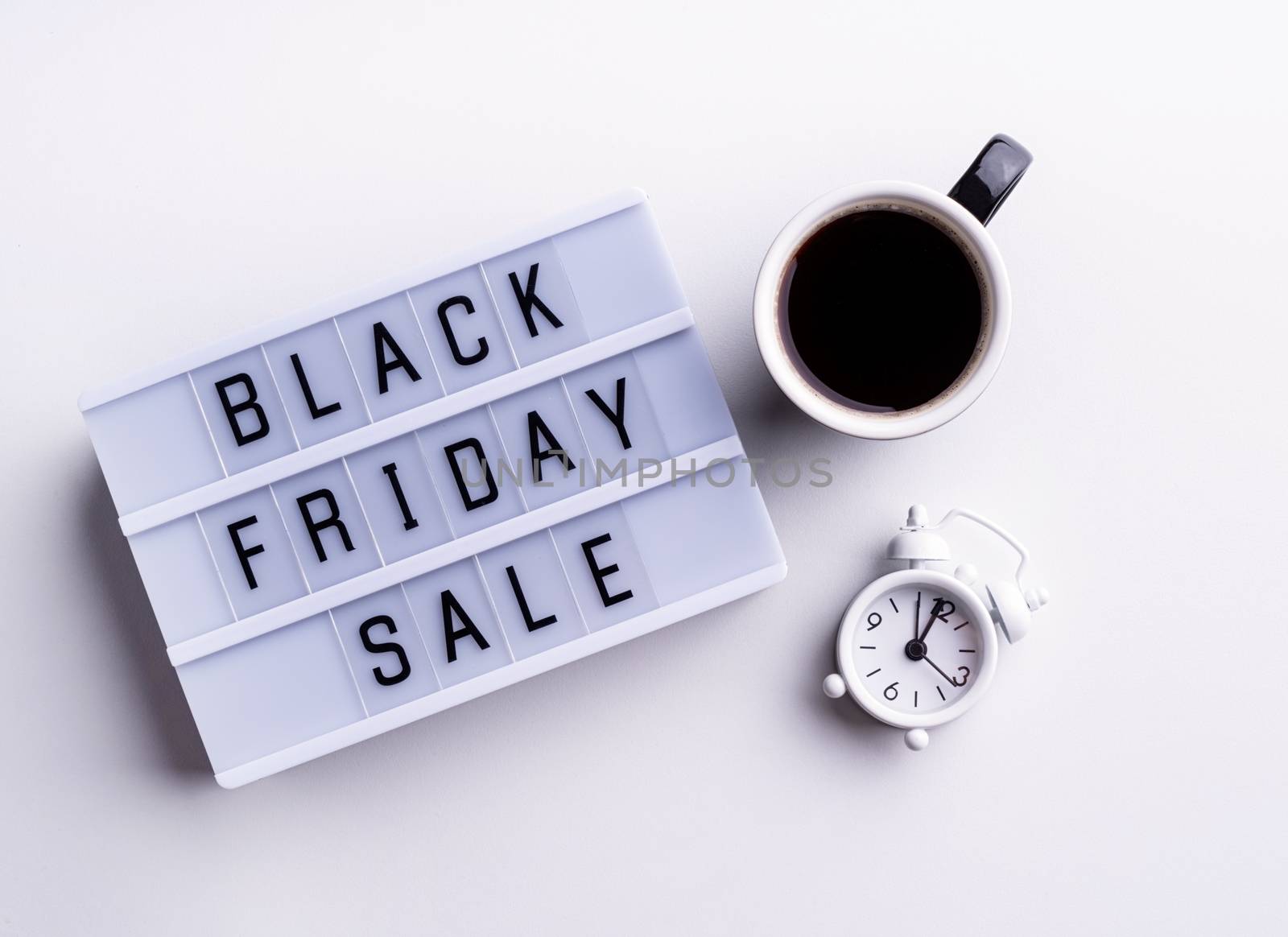 Black Friday Sale words on lightbox with cup of coffee and clock top view flat lay on white background by Desperada