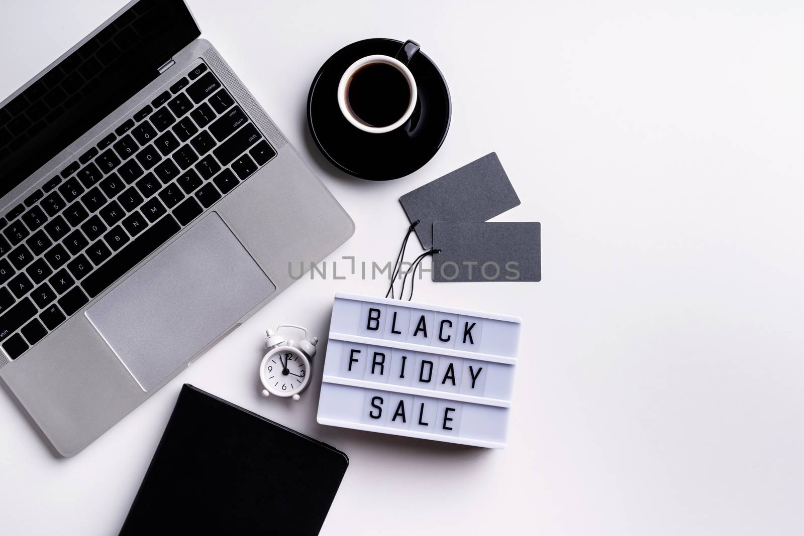 Black Friday Sale words on lightbox with cup of coffee, laptop and clock top view flat lay on white background by Desperada