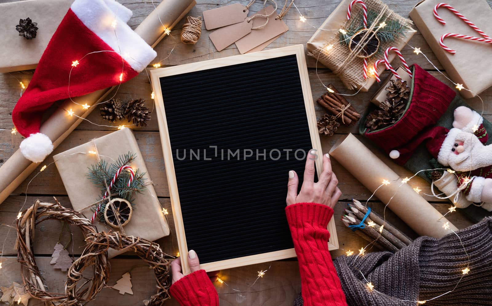 Zero waste and eco friendly christmas concept. Female hands holding blank letter board with christmas gifts and eco friendly decorations top view flat lay