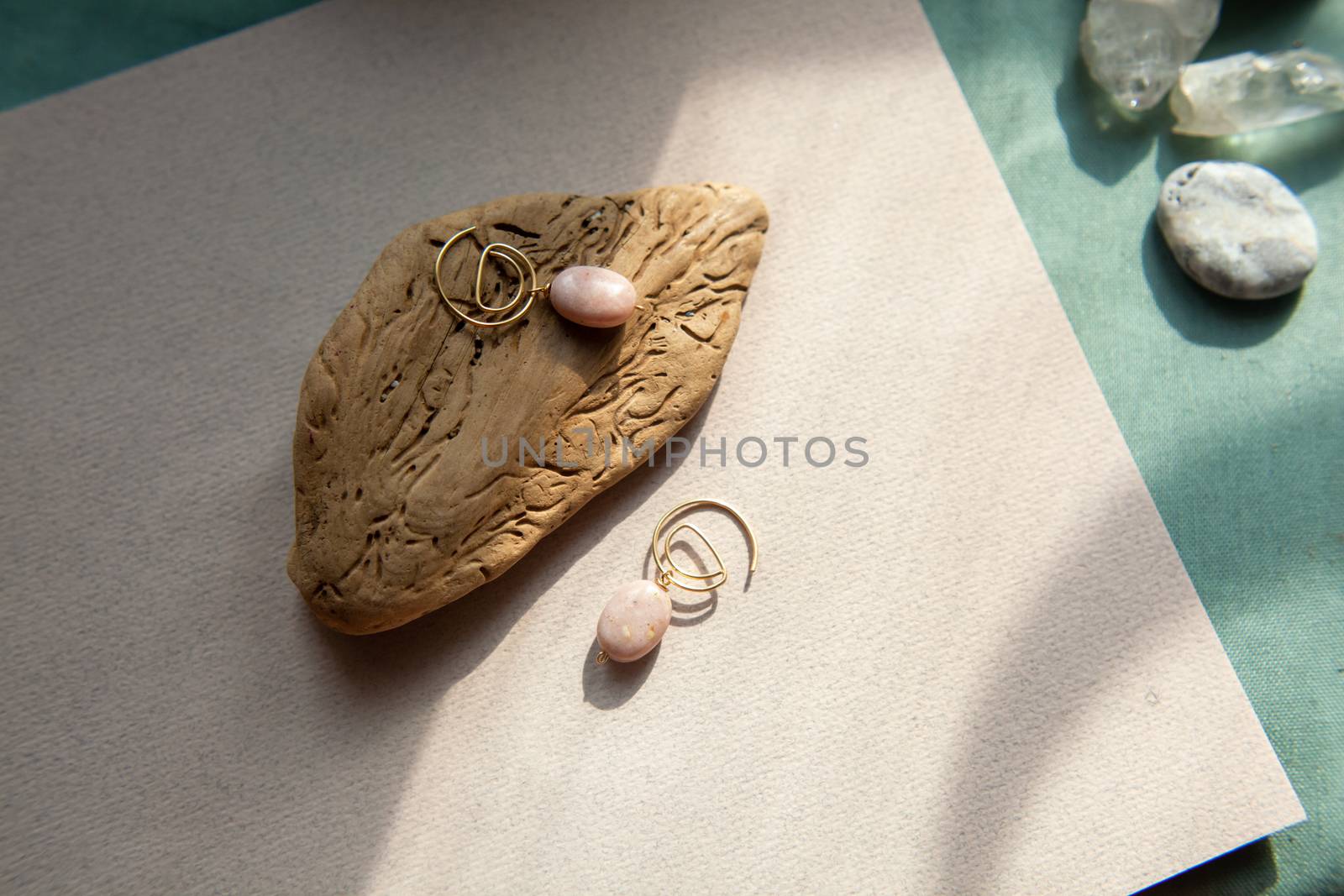 Stylish earrings made natural pink opal stone with Golden brass fittings piece of wood pattern from activity bark beetle. Natural day solar lighting.