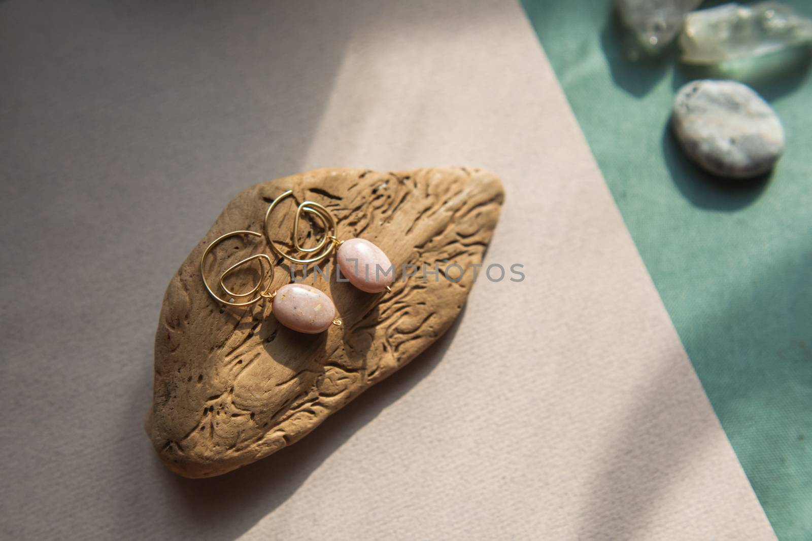 Stylish earrings made natural pink opal stone with Golden brass fittings piece of wood pattern from activity bark beetle. Natural day solar lighting.
