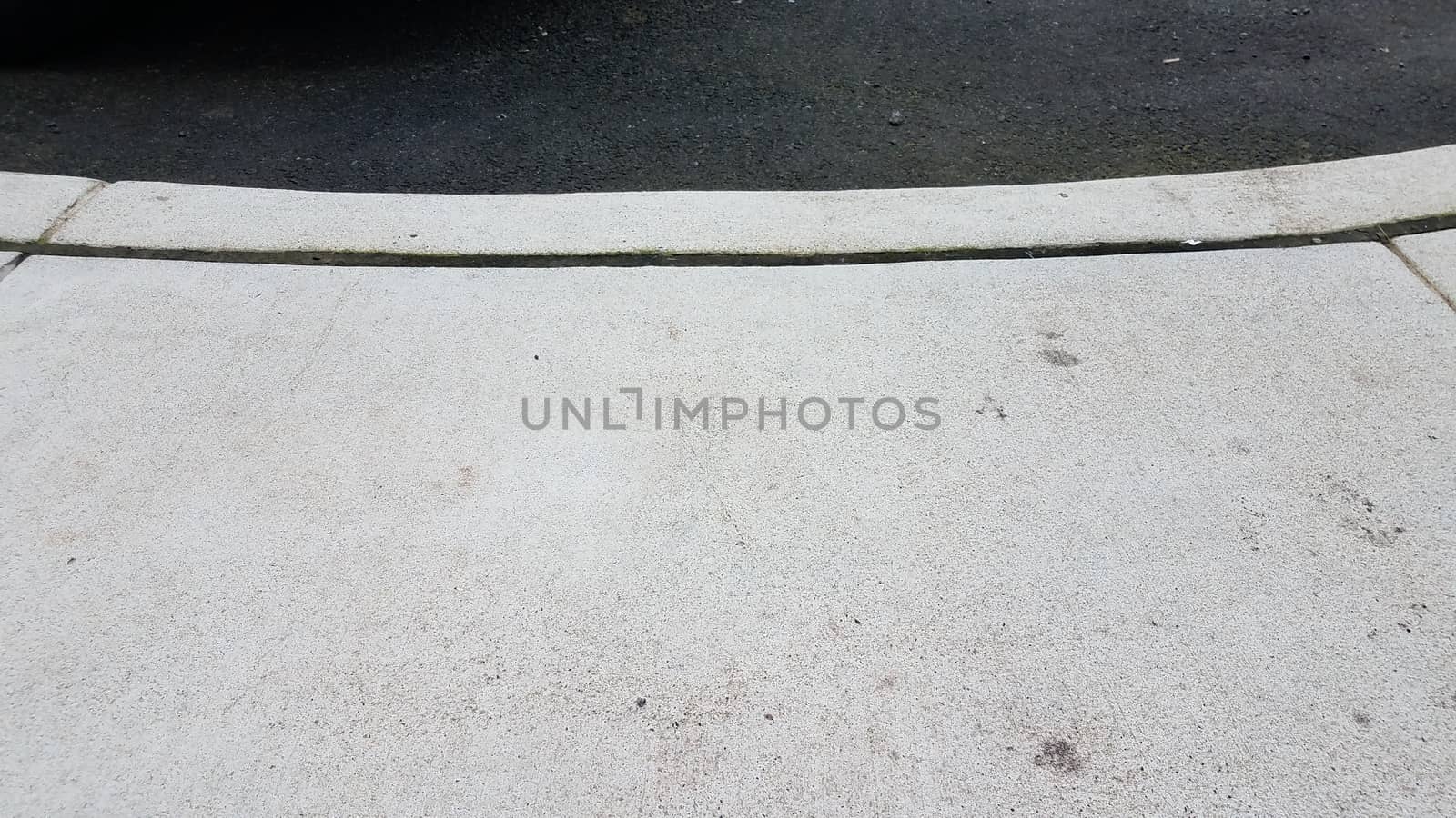 grey cement sidewalk and curb with asphalt by stockphotofan1