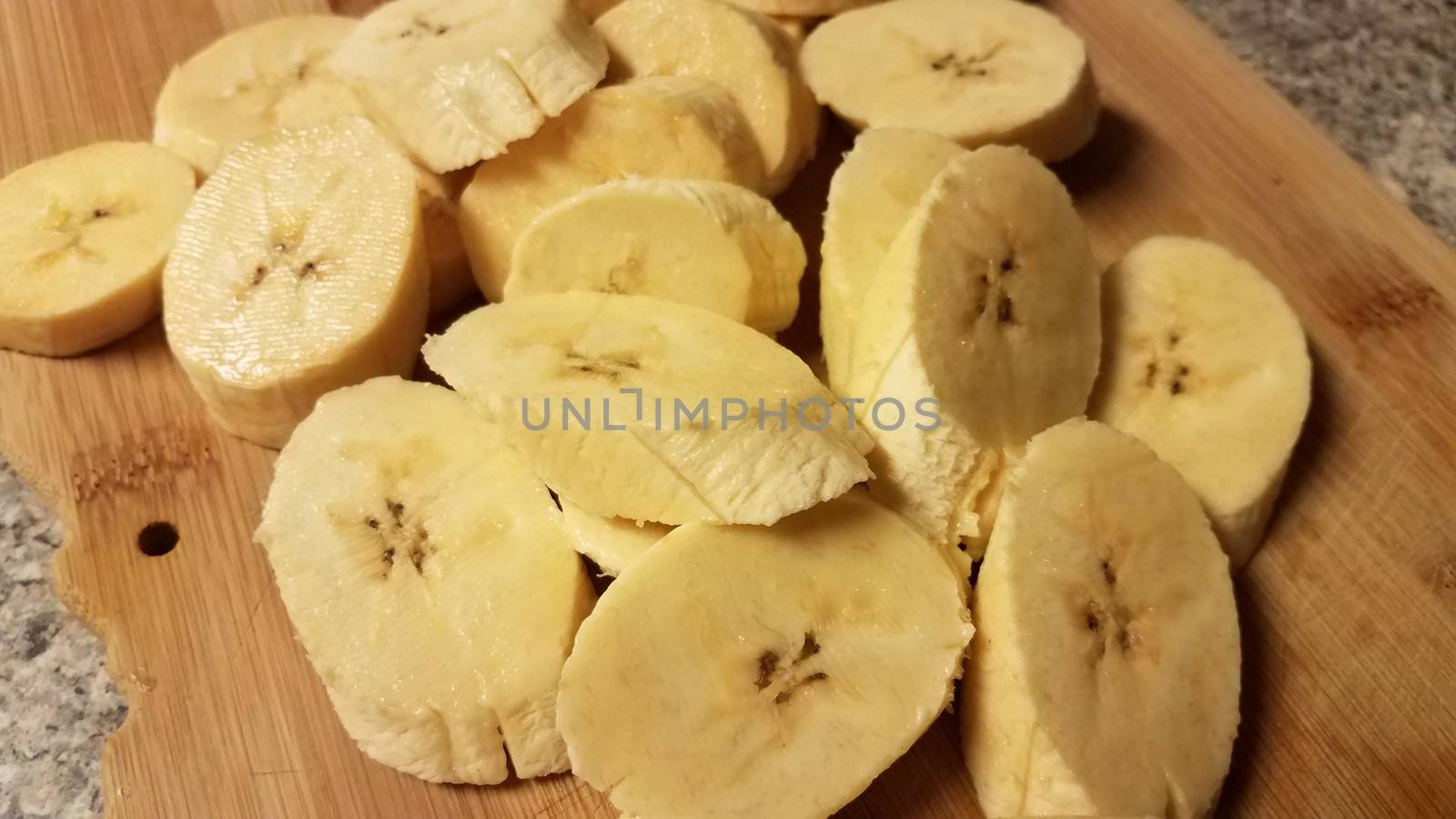 sliced plantain banana on wood cutting board by stockphotofan1