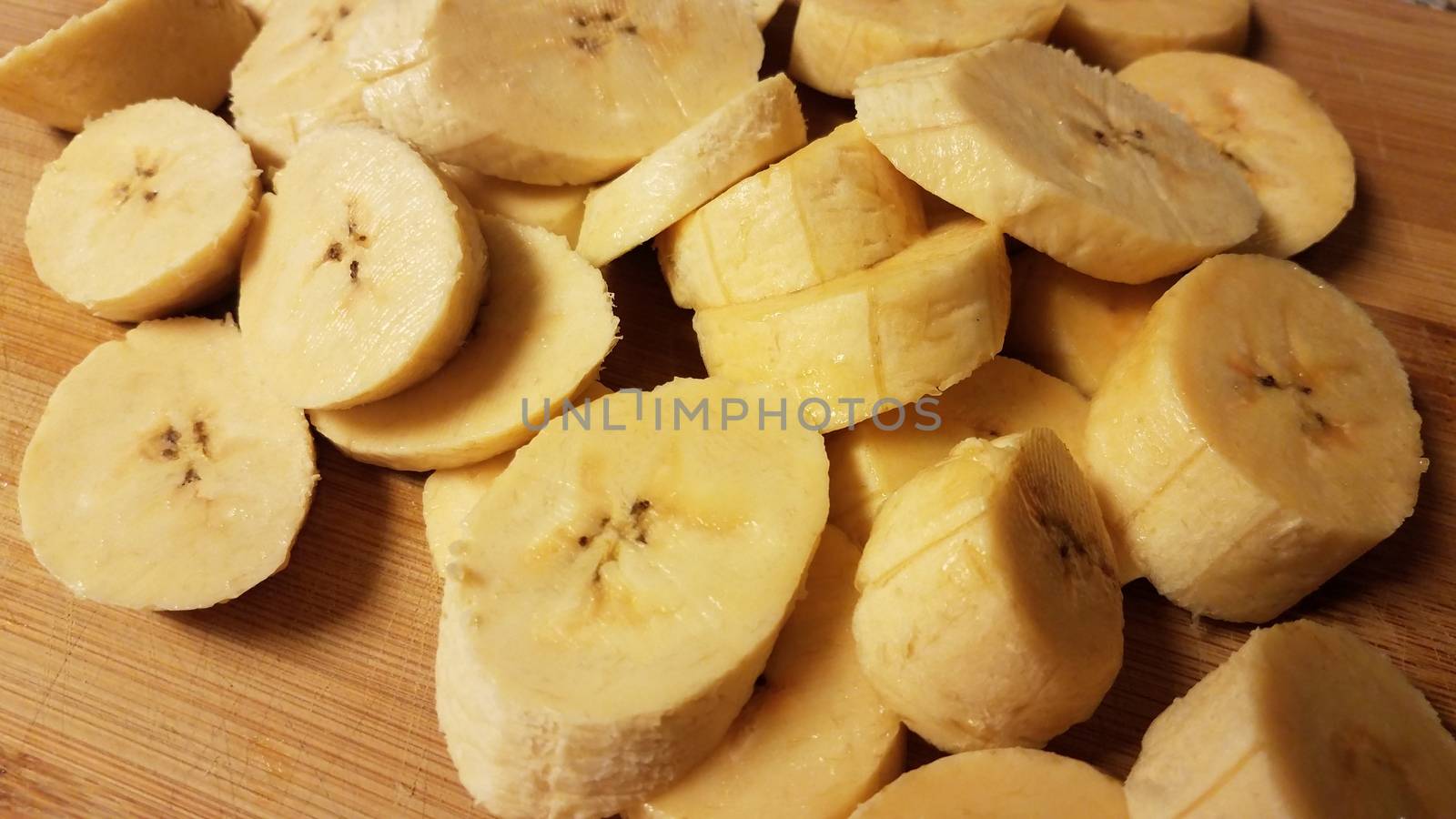 sliced plantain banana on wood cutting board by stockphotofan1