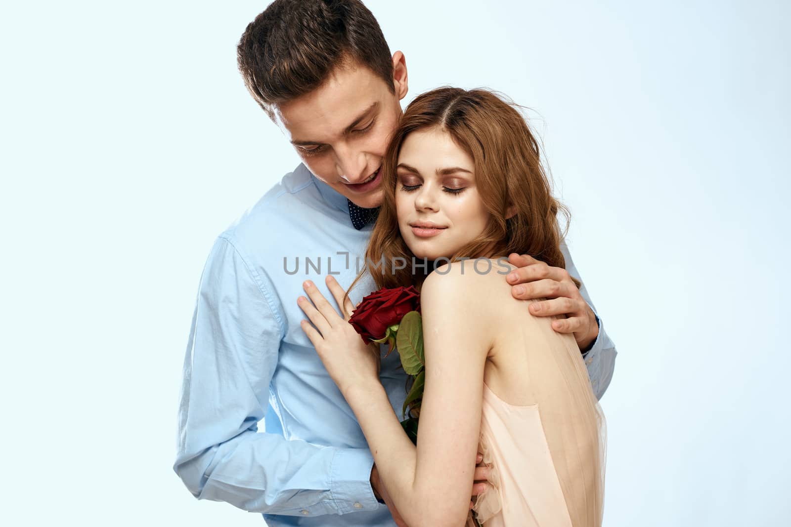 Man and woman with a red rose on a light background love family hugs by SHOTPRIME