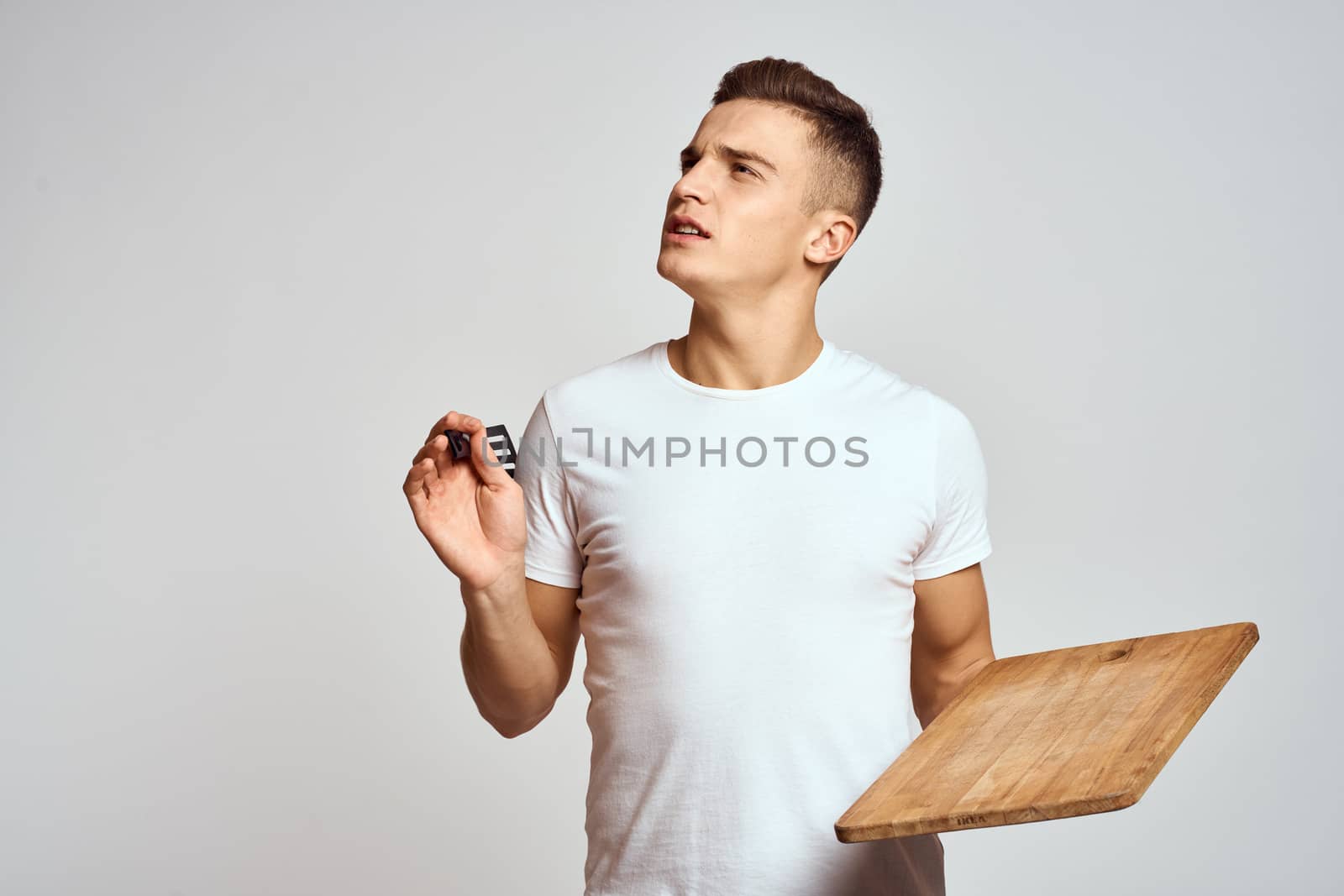 Guy with kitchen tools in hands on a light background cropped view of emotions fun model. High quality photo