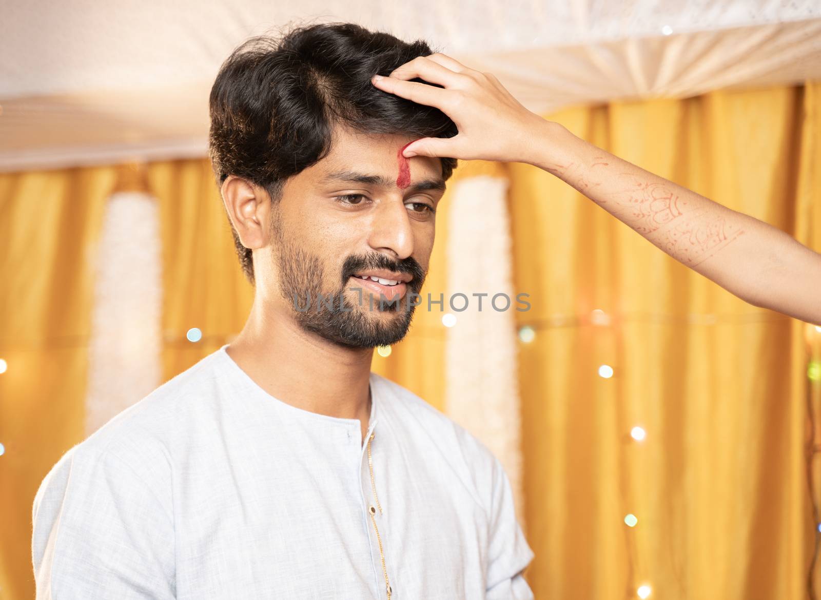 Close up Hands of Sister applying Tilak or mark to forehead of elder Brother during Bhai Dooj or Bhaubeej Indian religious festival by lakshmiprasad.maski@gmai.com