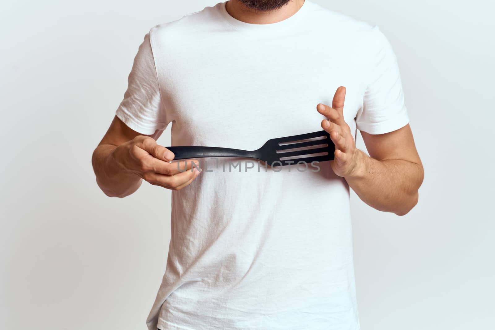 man with shovel for cooking white t-shirt cropped view light background. High quality photo