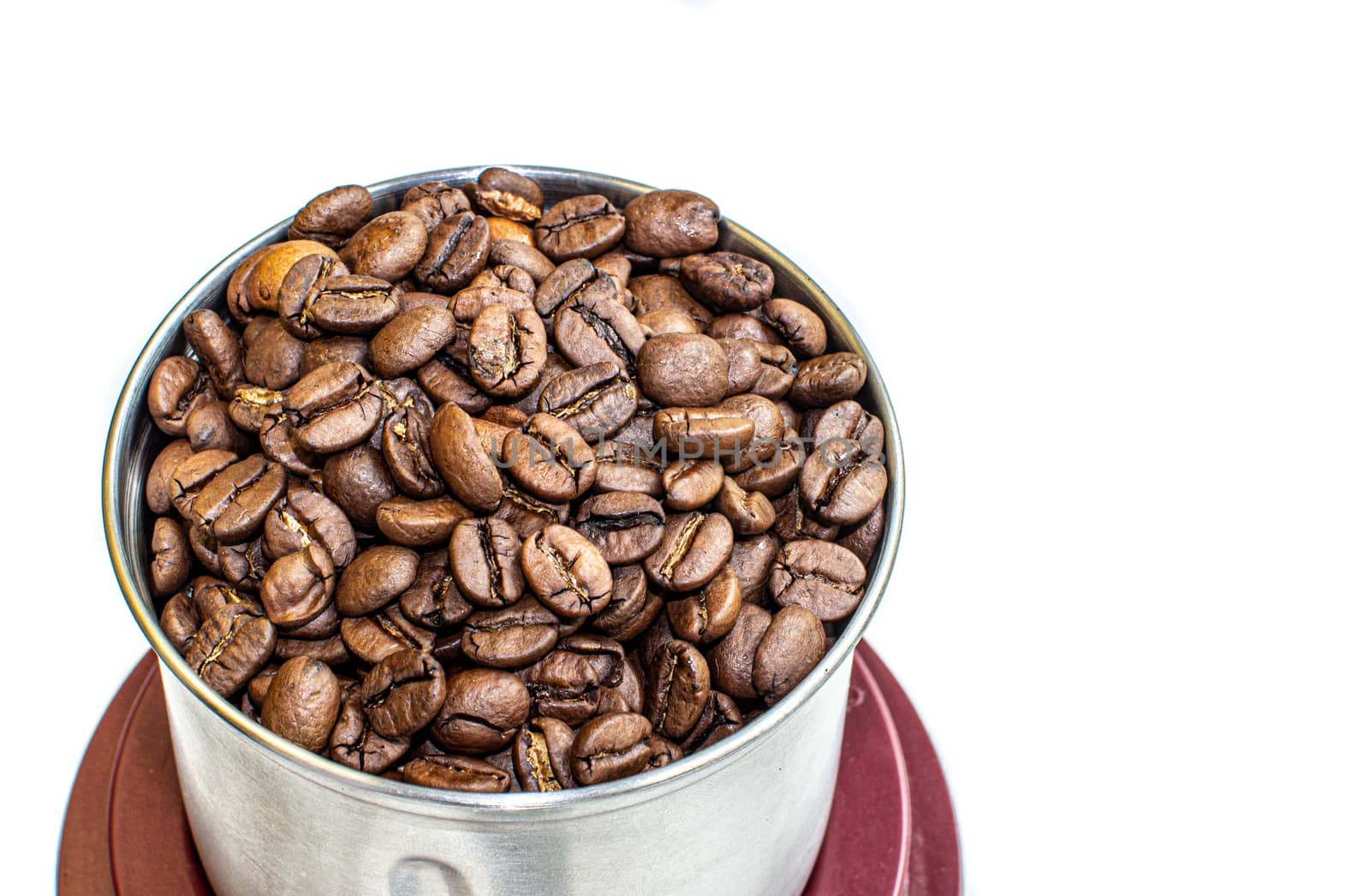 A lot of coffee beans in a metal coffee grinder on a white background. Isolated coffee items