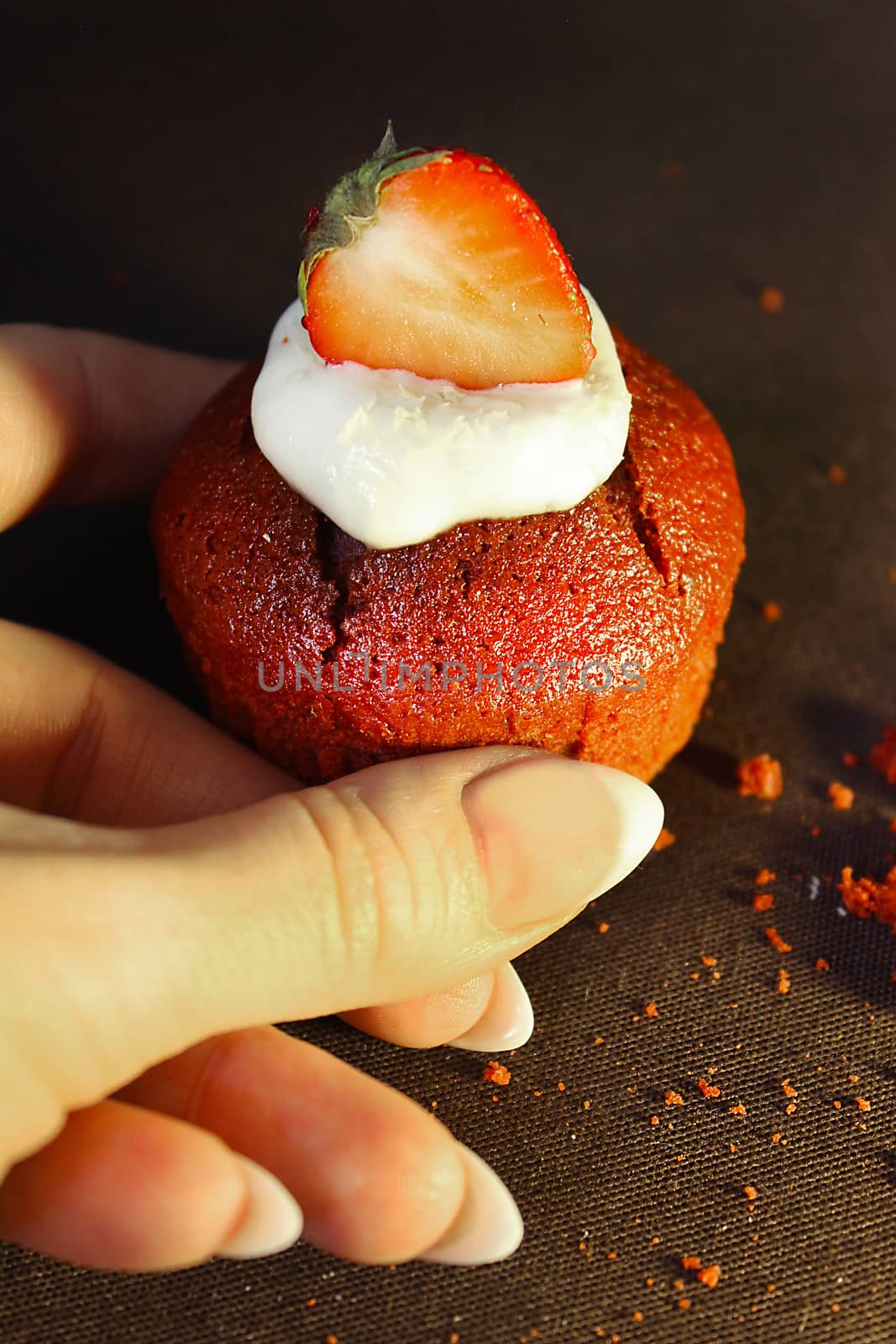 A woman's hand holds a strawberry cupcake .Texture or background