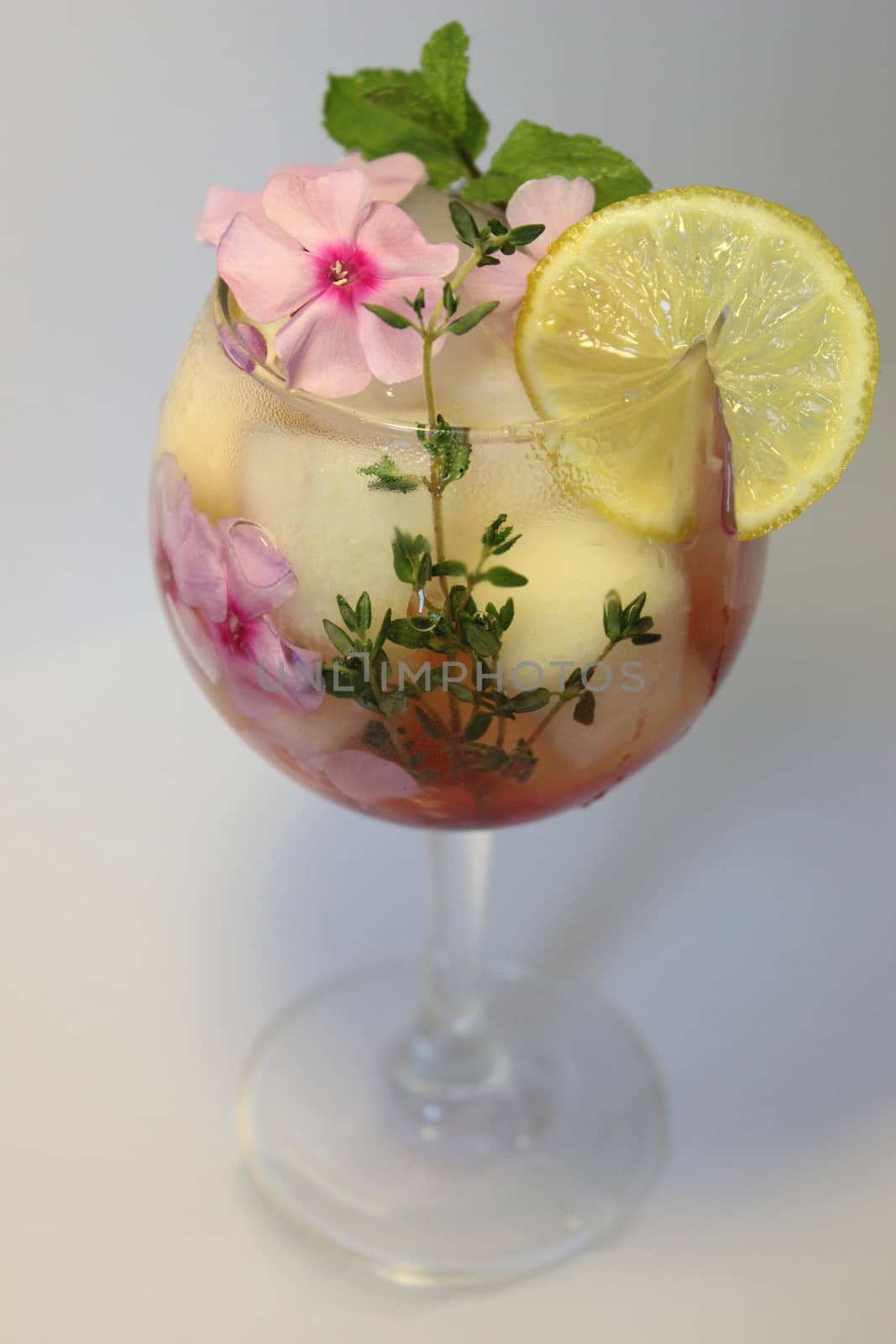 Chilled fruit tea with ice cubes and garnished with a sprig of mint