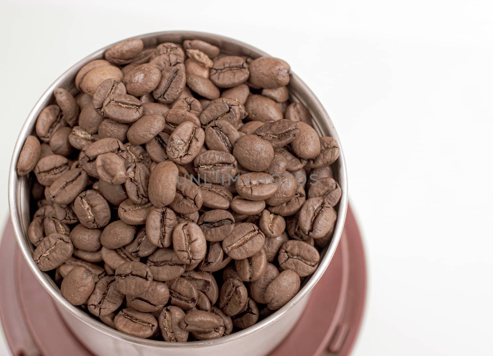 A lot of coffee beans in a metal coffee grinder on a white background. Isolated coffee items