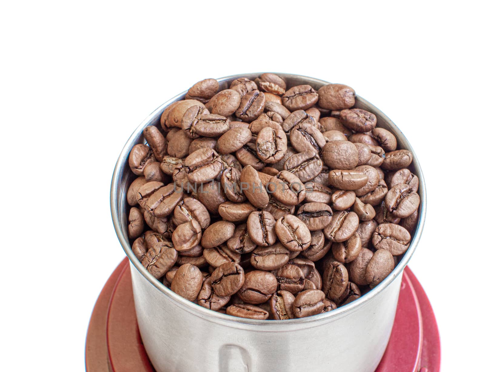 A lot of coffee beans in a metal coffee grinder on a white background. The view from the top. Isolated