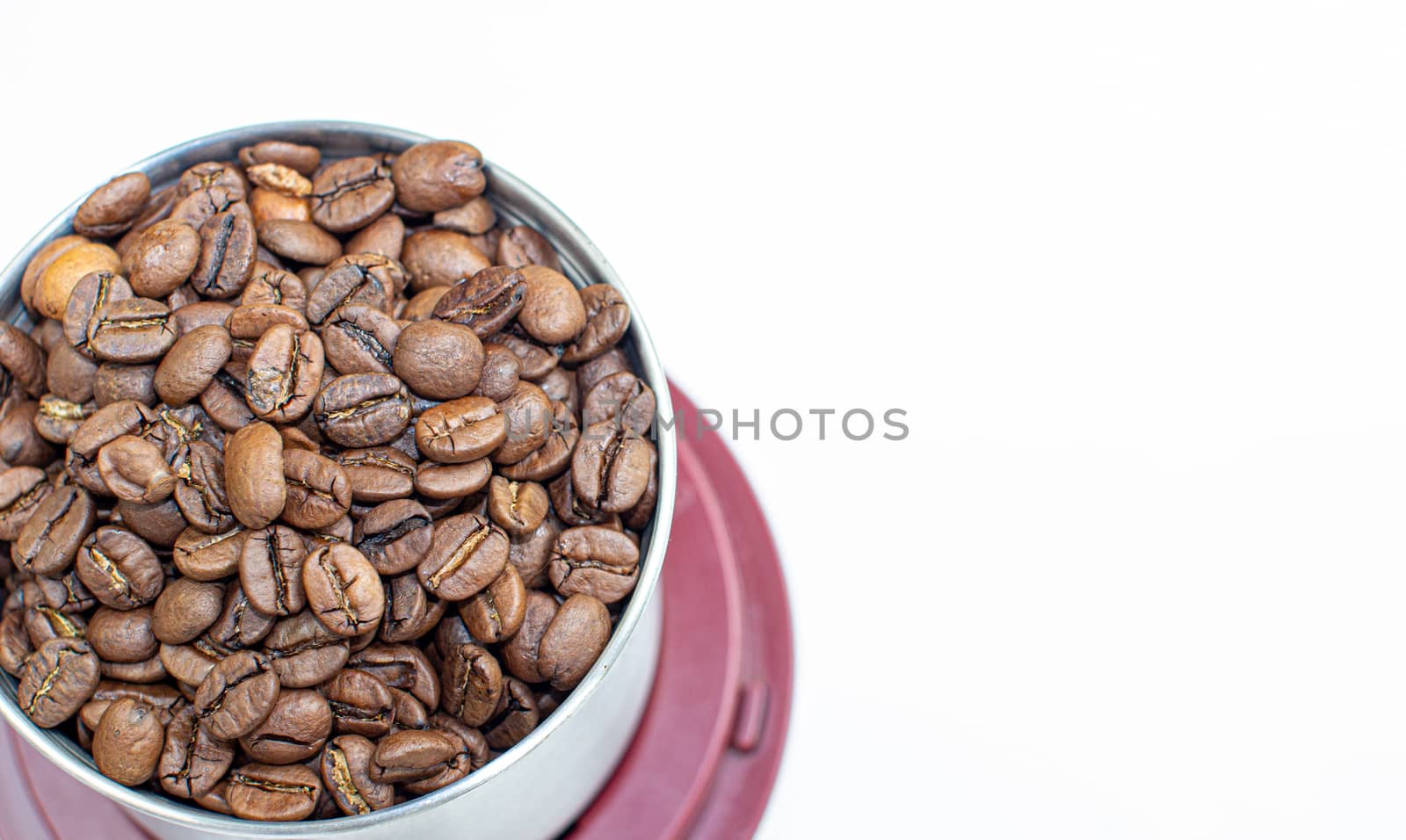 A lot of coffee beans in a metal coffee grinder on a white background. Isolated 