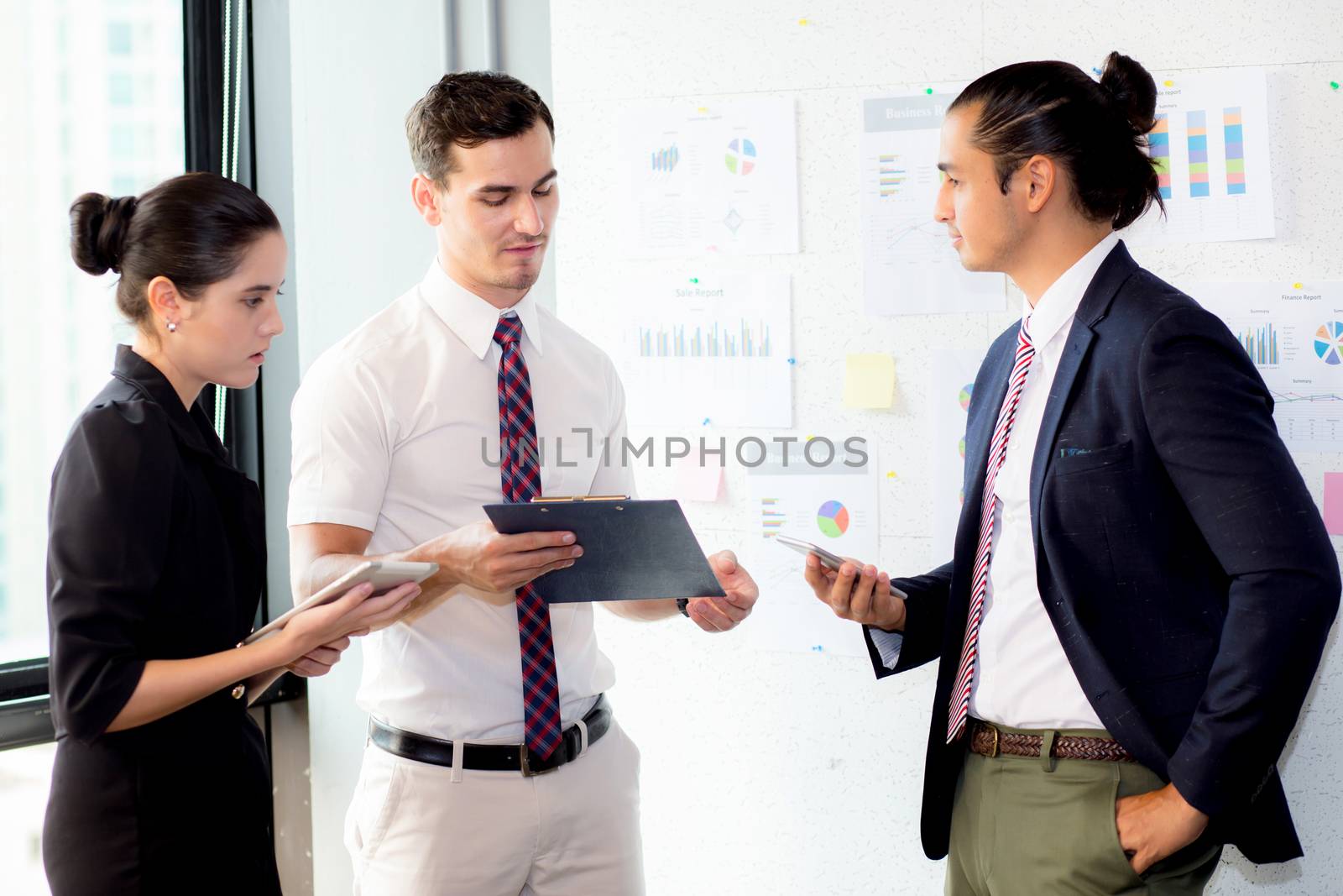 young businessman holding clipboard with present profit and secretary while giving presentation in office and talking business people other, teamwork concept.