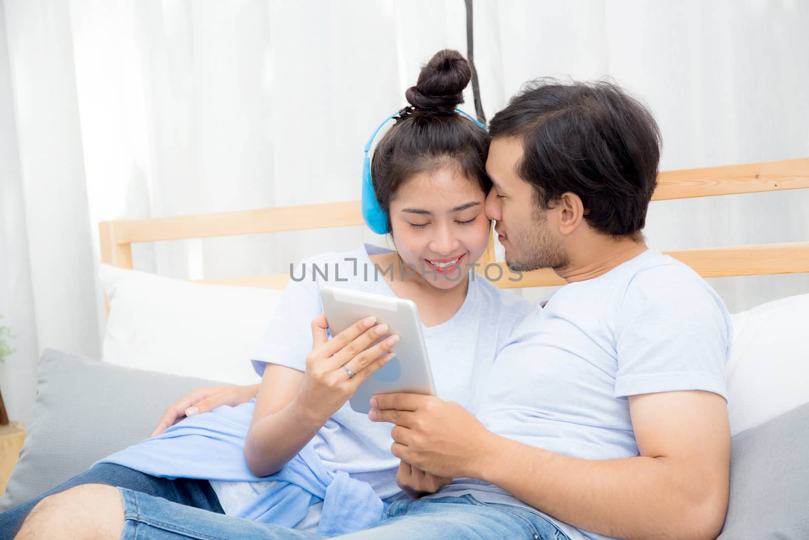 Beautiful asian young couple listening to music with tablet on bed, Love, dating,Young couple in sitting together in bed using a Tablet.