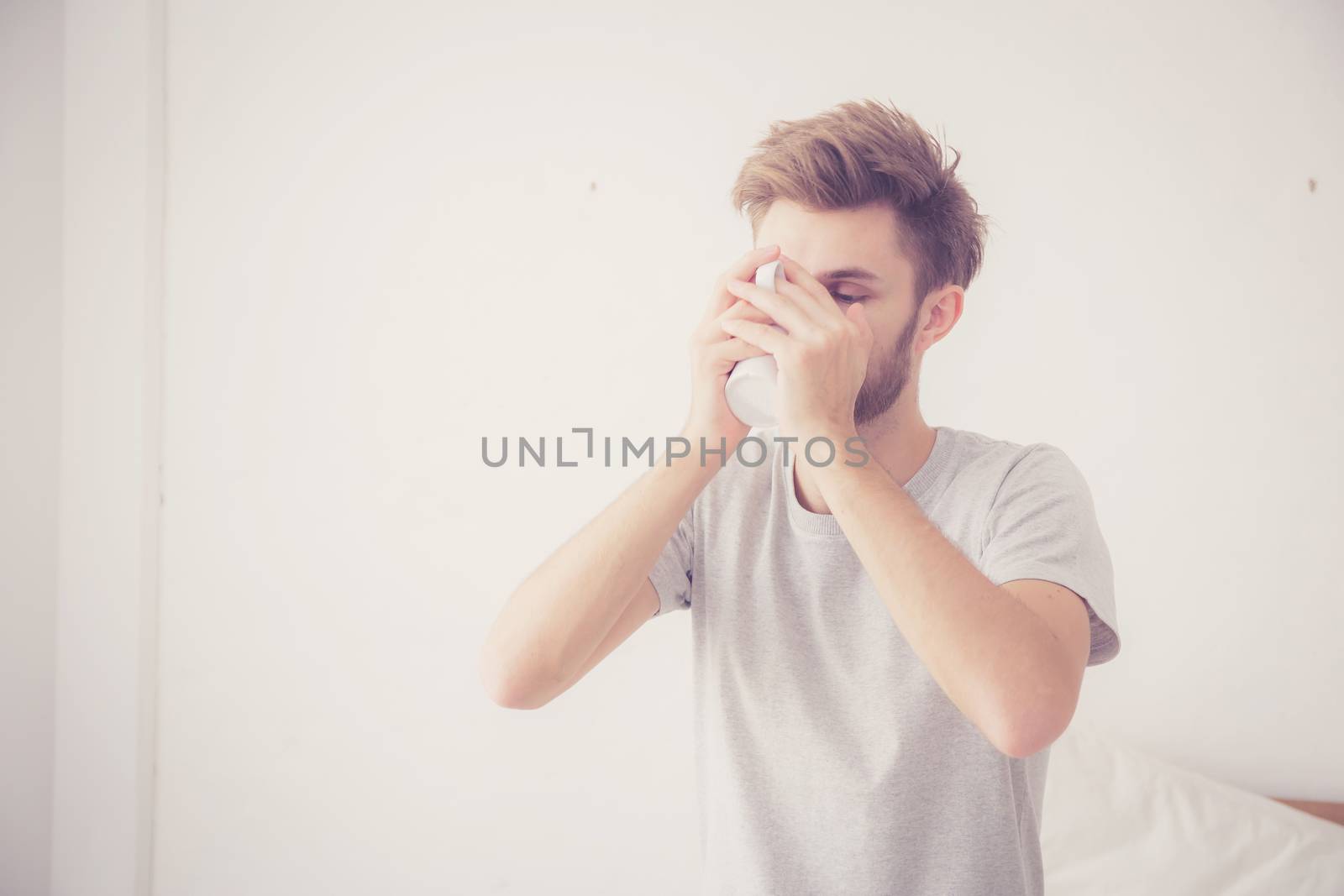 american man with cup of coffee in bedroom with morning.