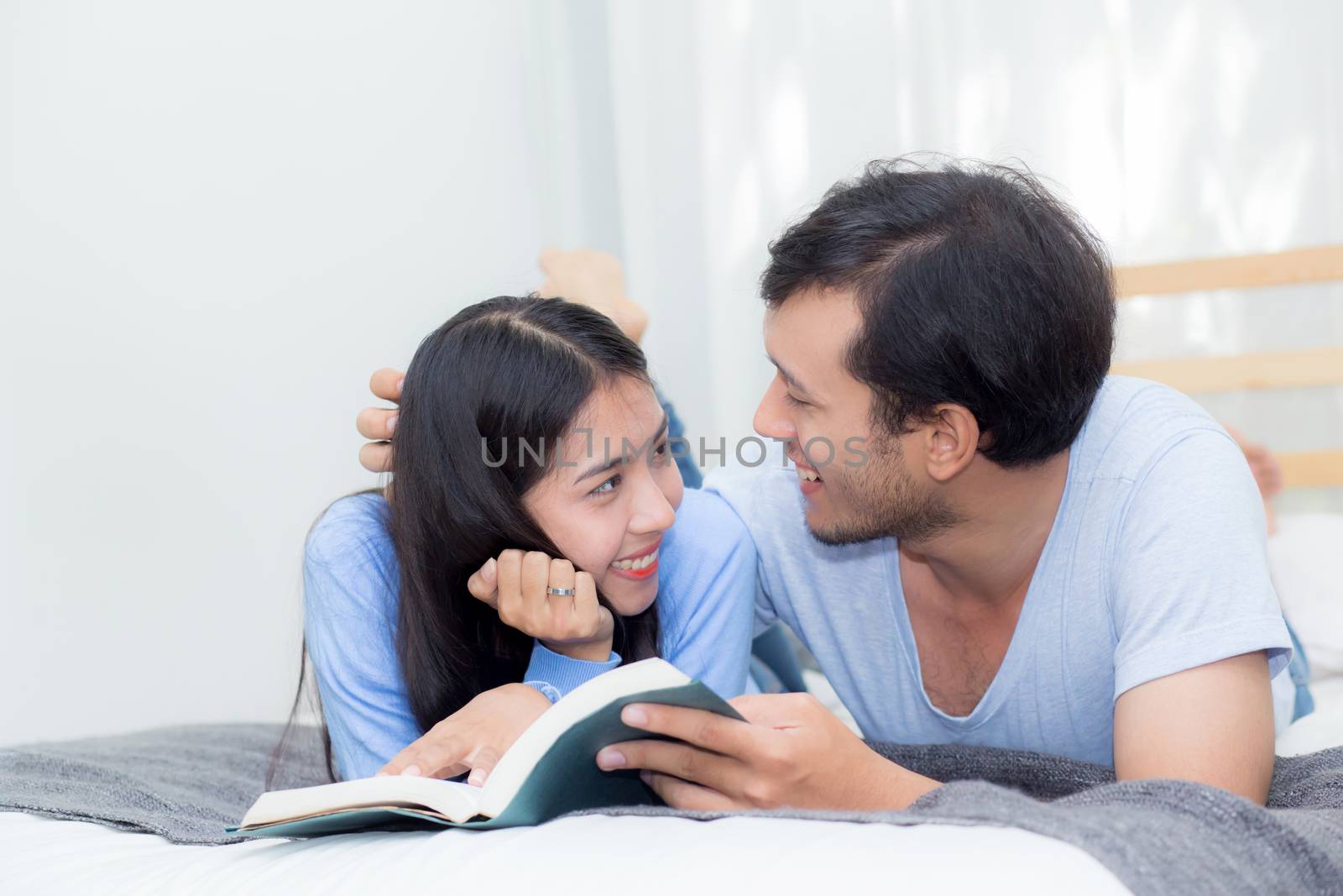 Couple reading a book together in bedroom on the morning with happiness.