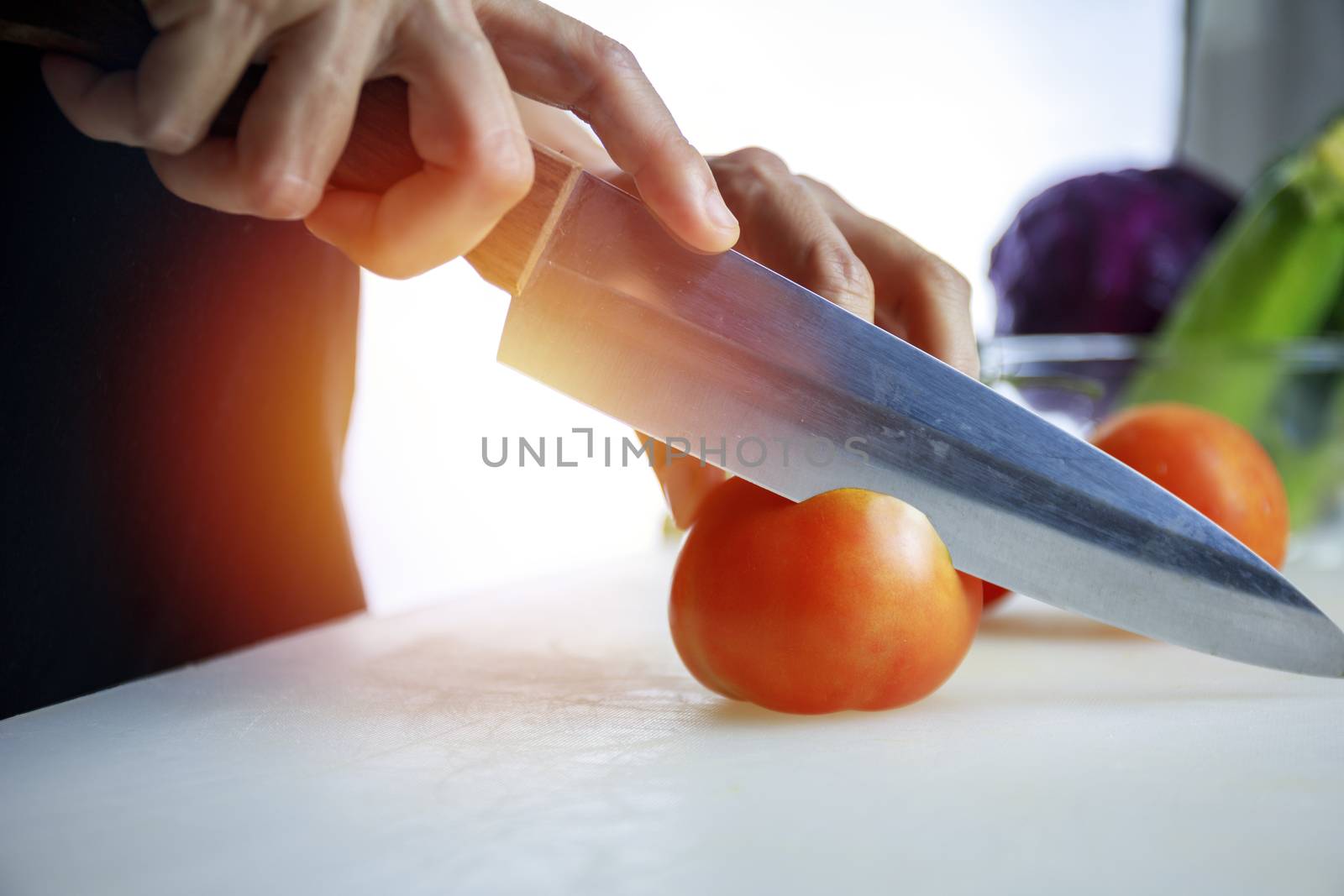Close up hands women holding knife and cuting fresh Courgette on Cutting Board. Female hand slices raw Japanese Cucumber into circles with knife on cutting Board. healthy food concept..