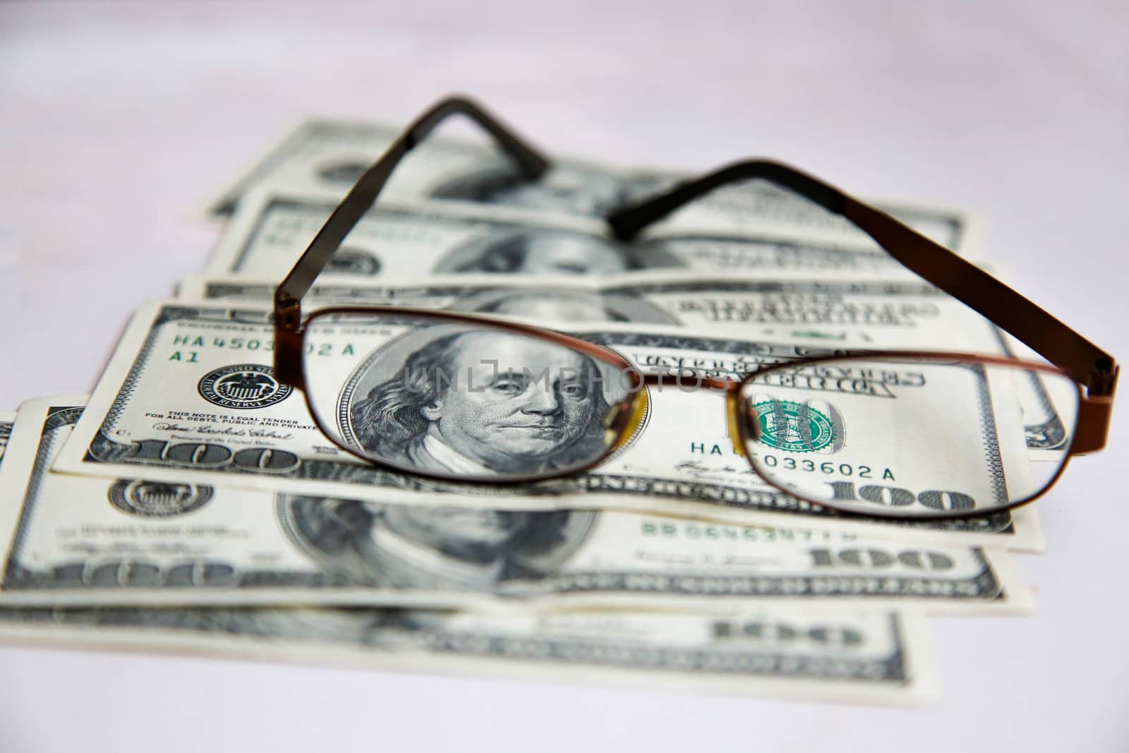 Glasses in a frame lie on dollars spread out on a white table.Texture.Background.