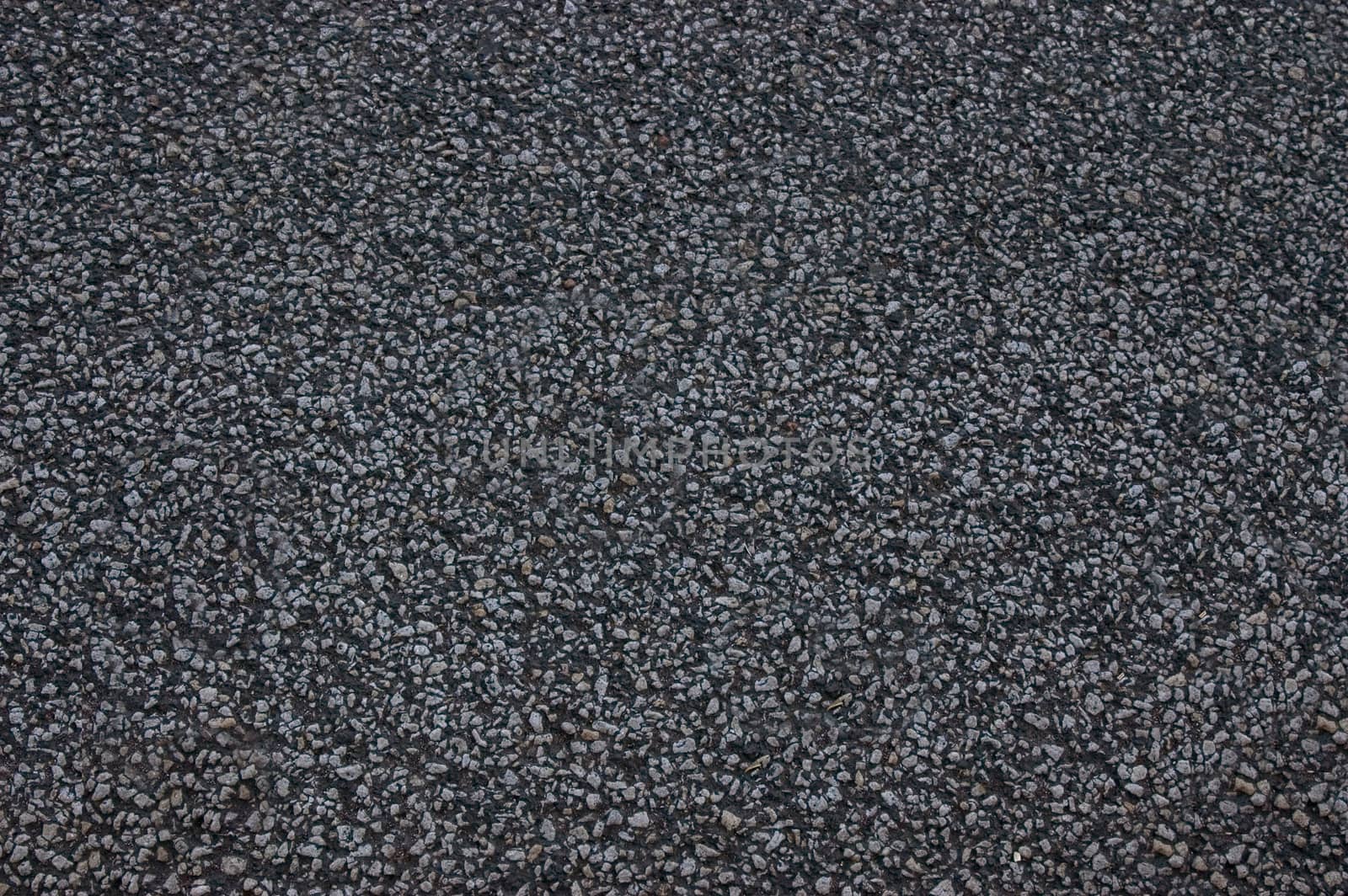 The asphalt road is black with uneven surface.Texture or background.