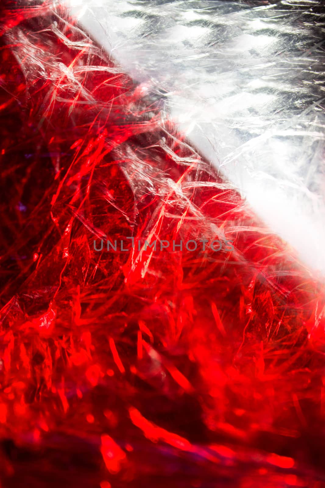 Heavily crumpled cellophane illuminated by white and red light . Texture or background