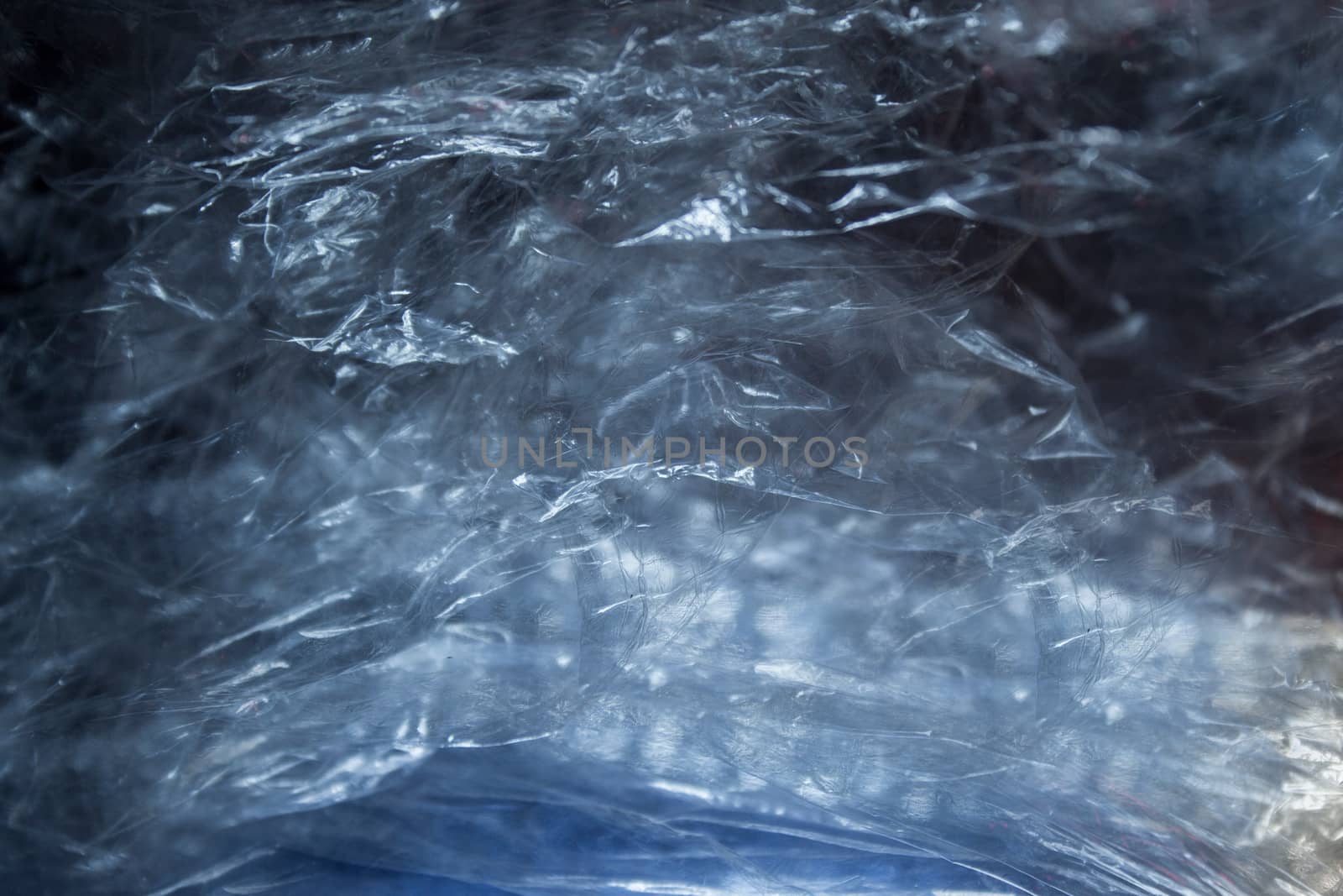 Crumpled transparent film with a blue sheen and textured surface.Texture or background