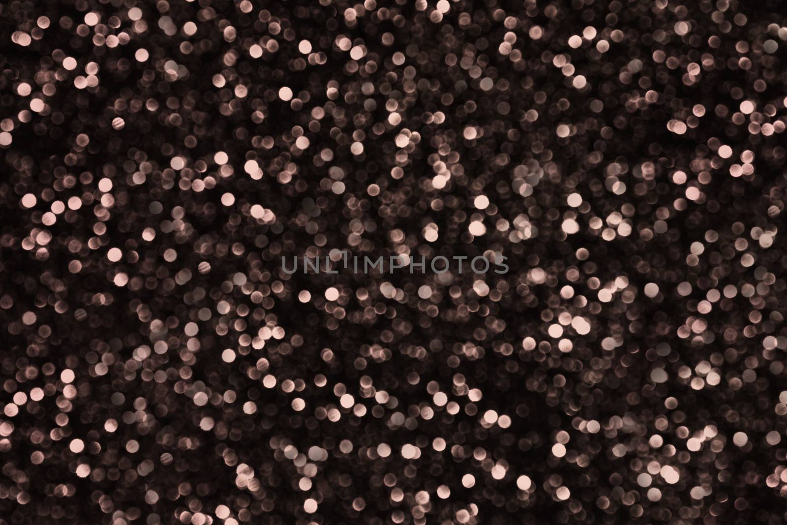 A large number of unfocused round small balls of brown color on a black background.Texture or background