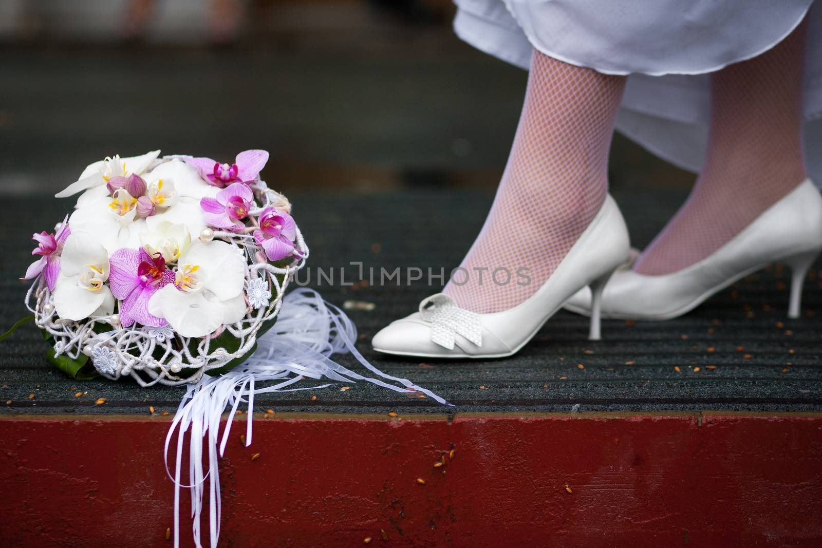 The bride in white wedding shoes stands near a beautiful wedding bouquet