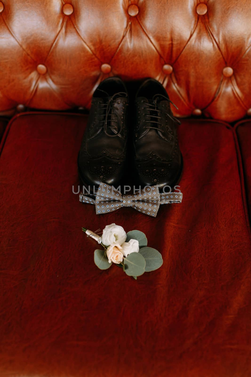Men's black wedding shoes are located on the leather sofa