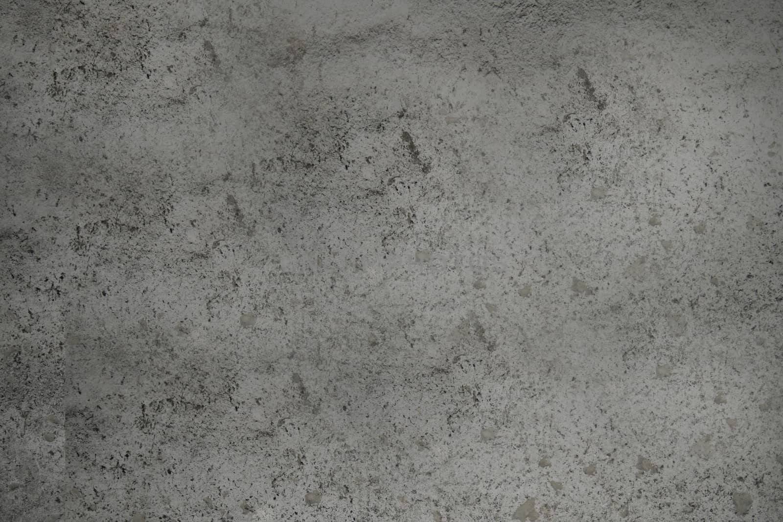 A dirty concrete wall of dark gray color with a textured surface .Texture or background