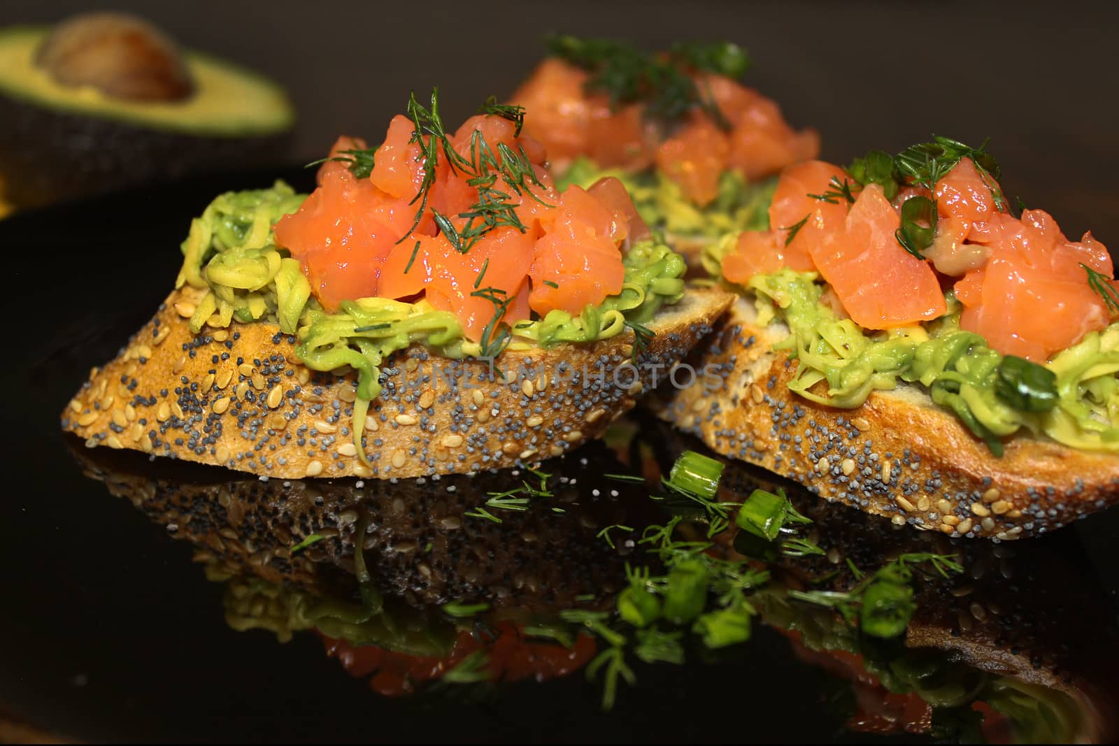 On a plate, sliced French baguette with salmon, herbs and avocado